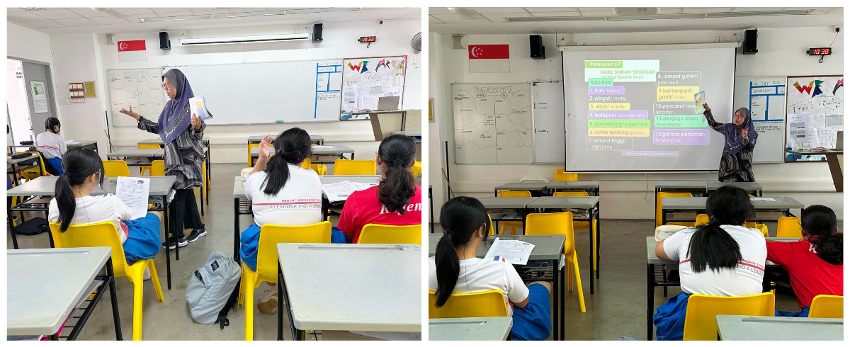 A teacher in a hijab instructs students seated at yellow chairs in a classroom, with a projected lesson on a screen.
