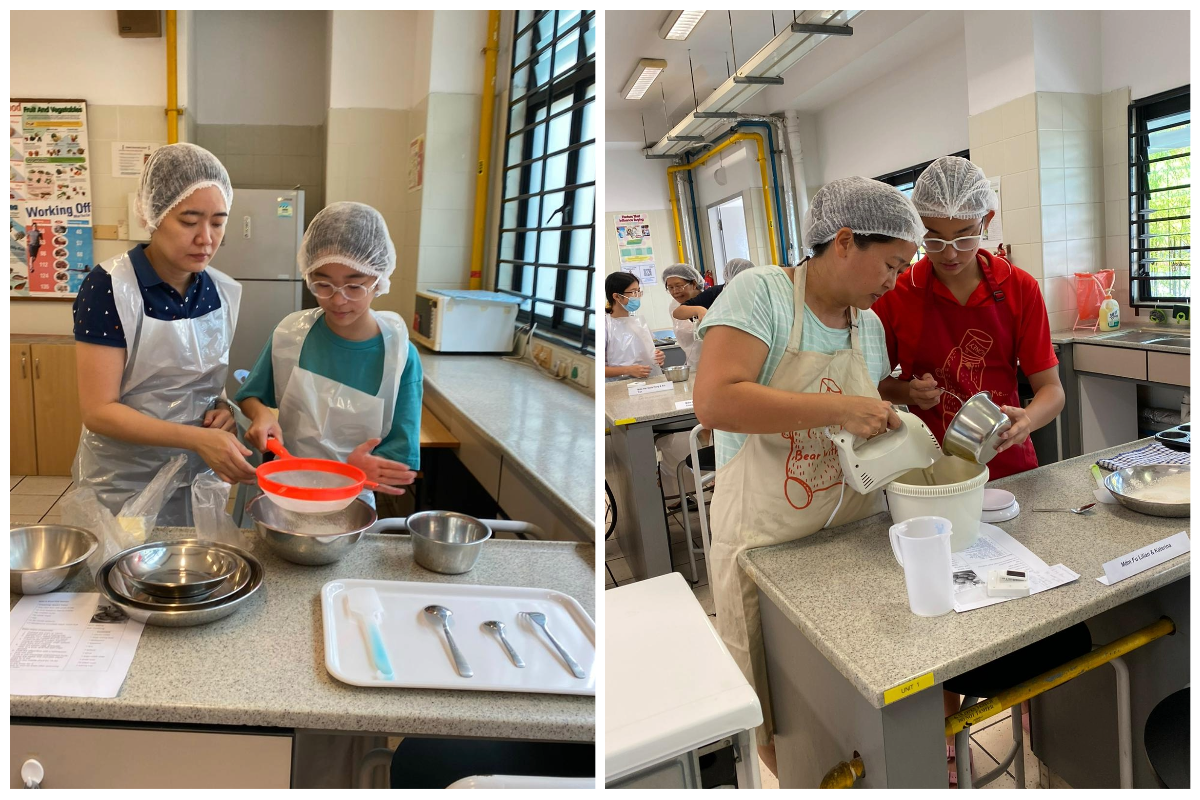 Two pairs of people wearing hairnets and aprons cook in a kitchen classroom, sifting flour and using a mixer.