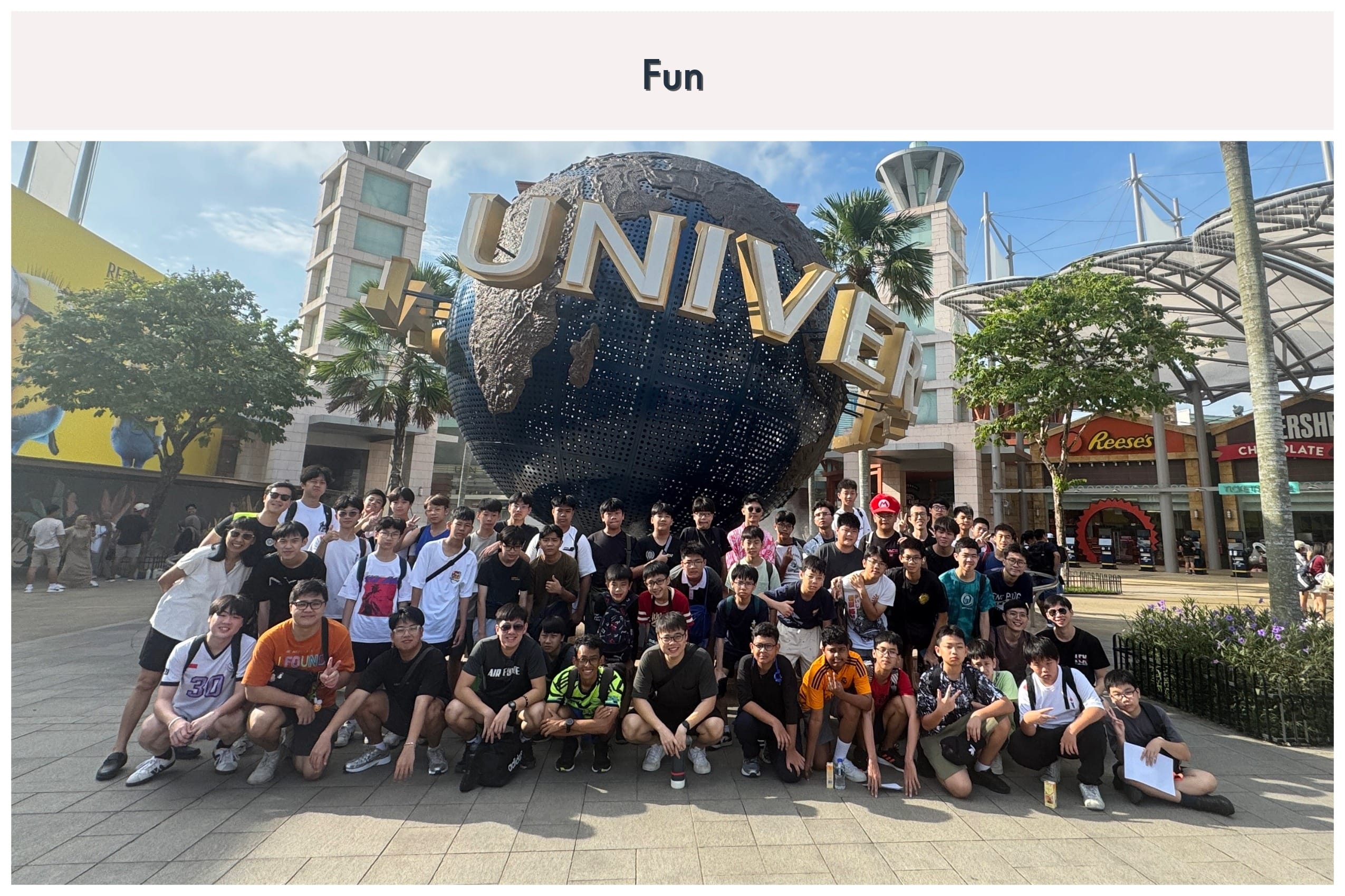 Large group of young people posing in front of the Universal Studios globe sculpture on a sunny day.