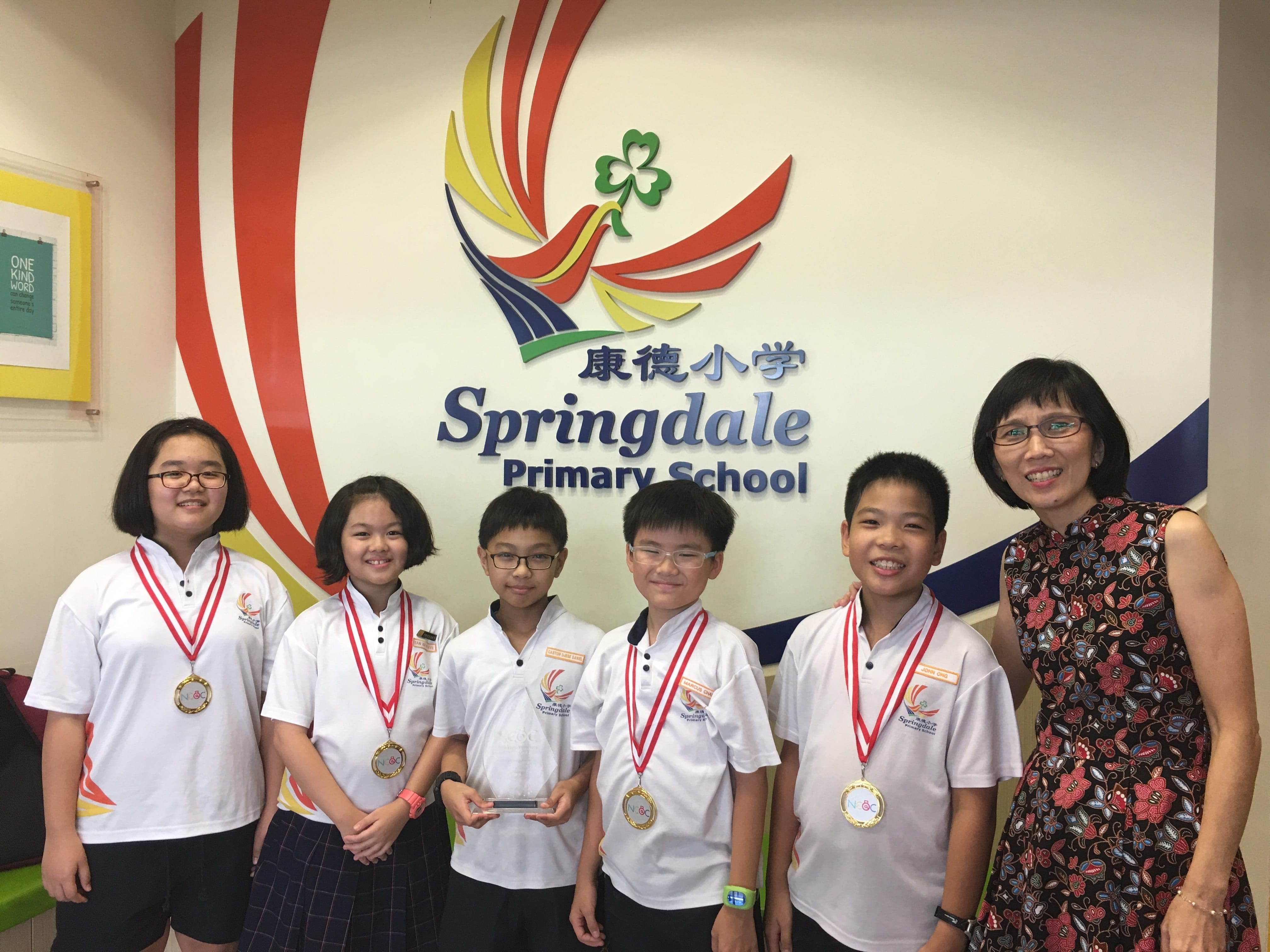 Five students wearing medals and a teacher pose in front of the Springdale Primary School sign.