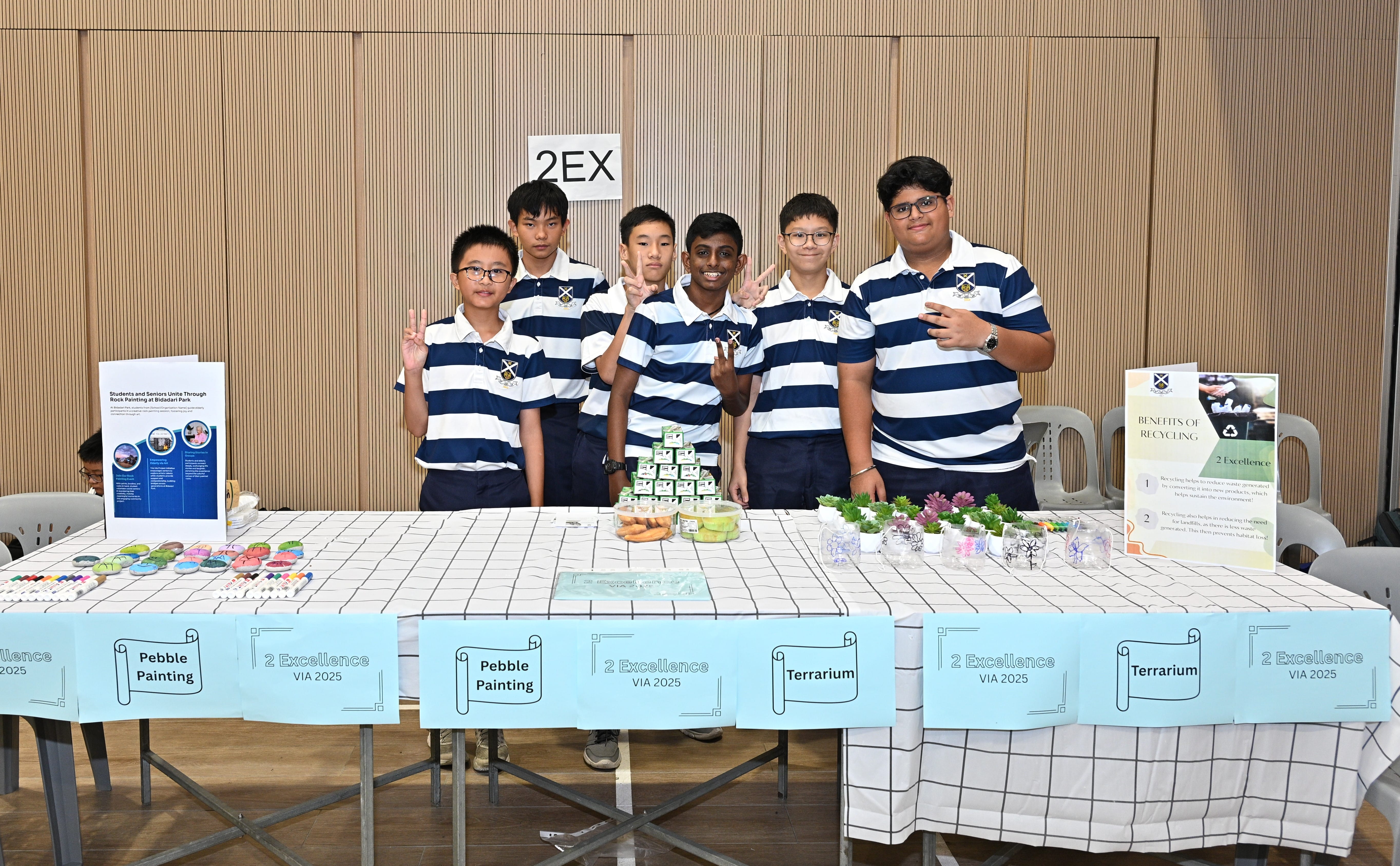 Students posing in front of a booth for Pebble Painting and Terrarium