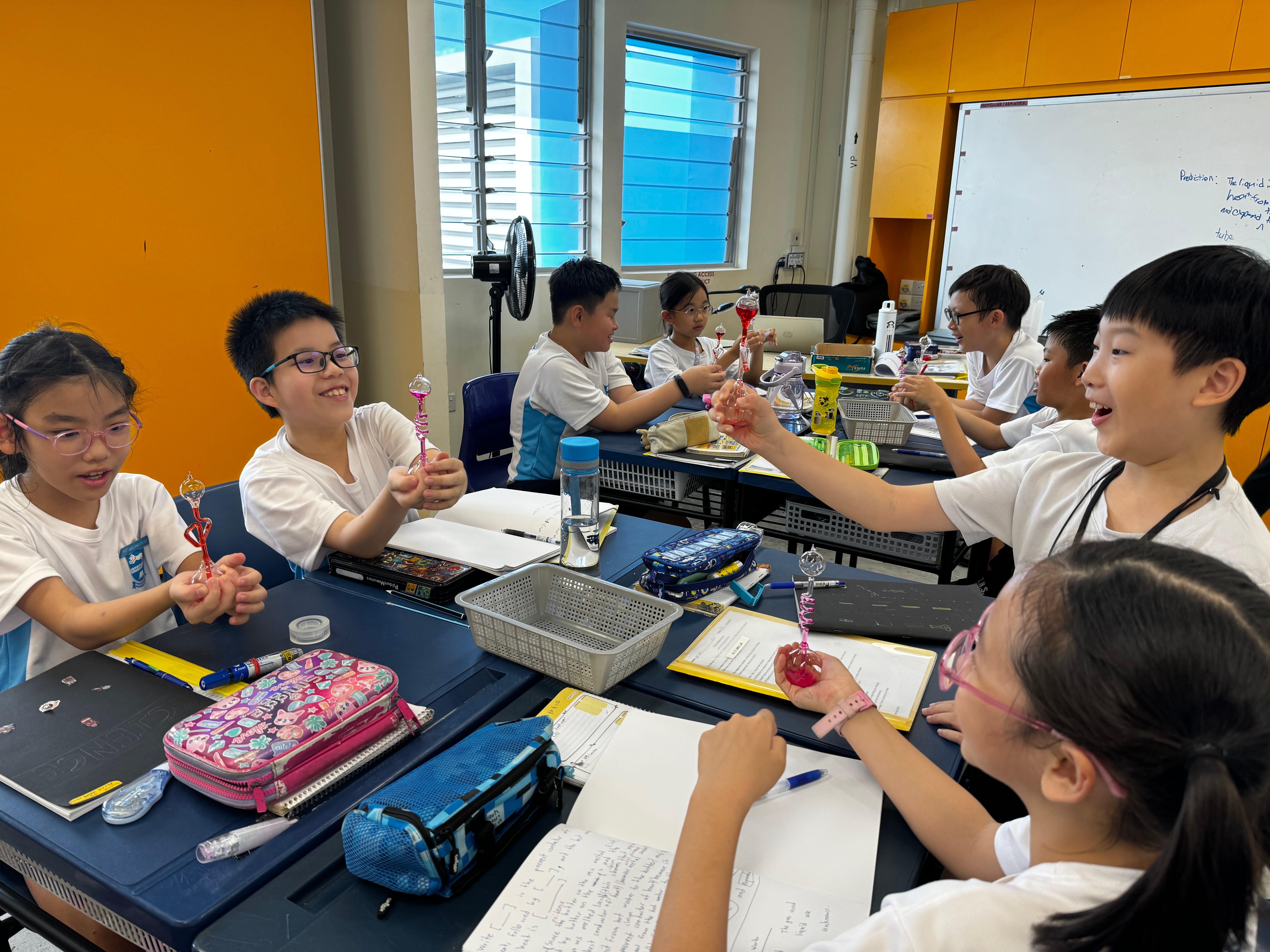 Students examine colourful glass instruments together during a science lesson.