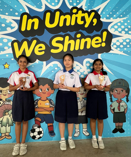 Three unity primary school students, Saanvi Salla and Charleen Ho from 6E, together with Trivedi Tanvi from 5E holding trophy from the competition