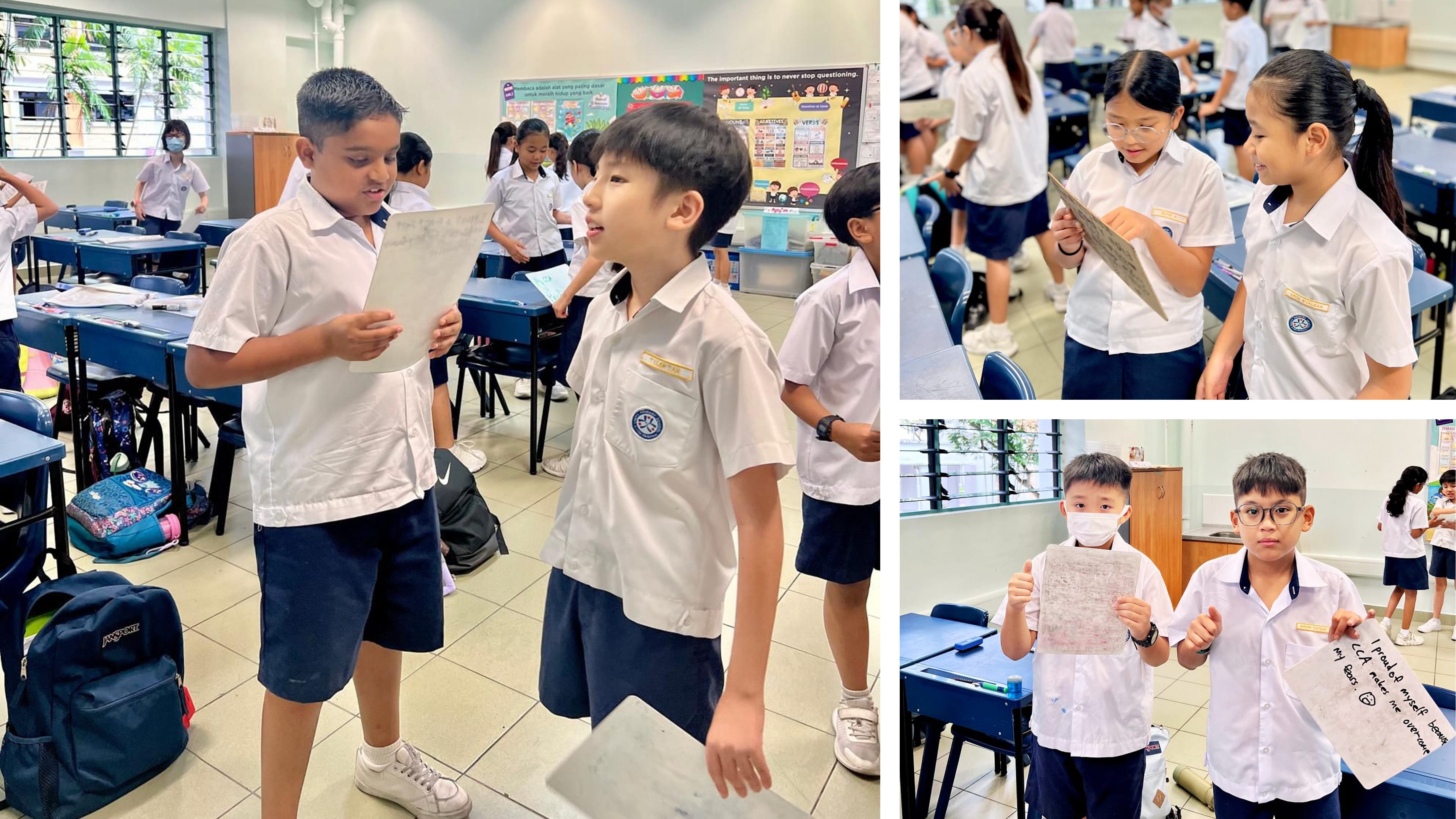 Primary school students in white uniforms share and discuss written papers with each other inside a classroom.
