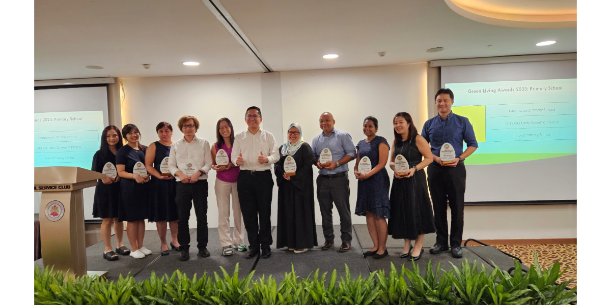 Group of people standing on a stage holding awards at the Green Living Awards 2023 Primary School ceremony.
