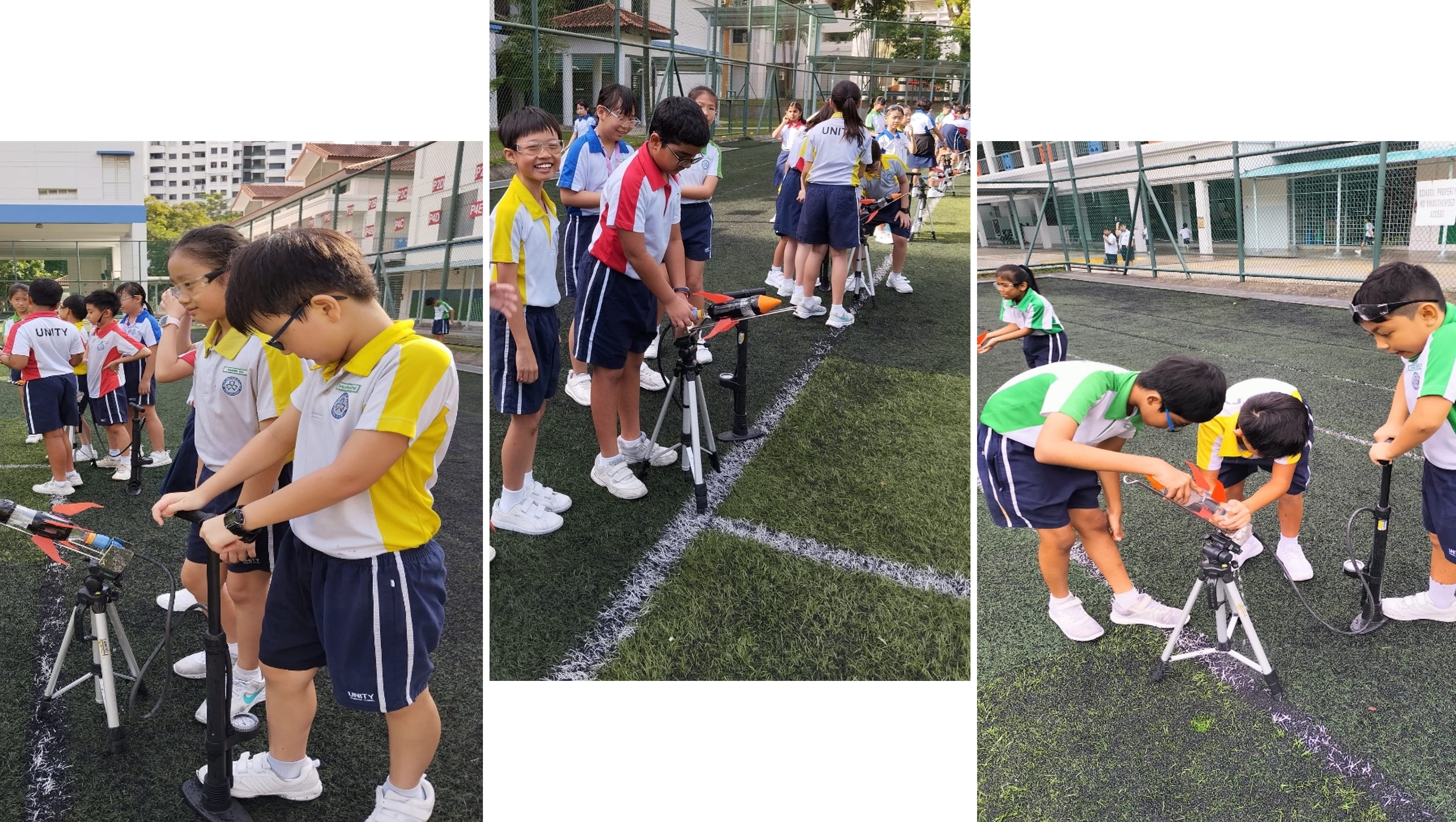 School children in uniforms launch small rockets on tripods on a green sports field outdoors.
