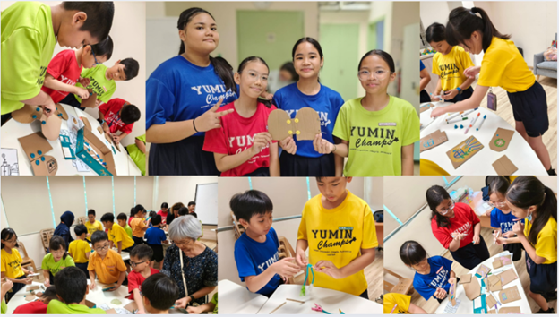 Children wearing school shirts work on cardboard craft projects for an Outreach Programme.