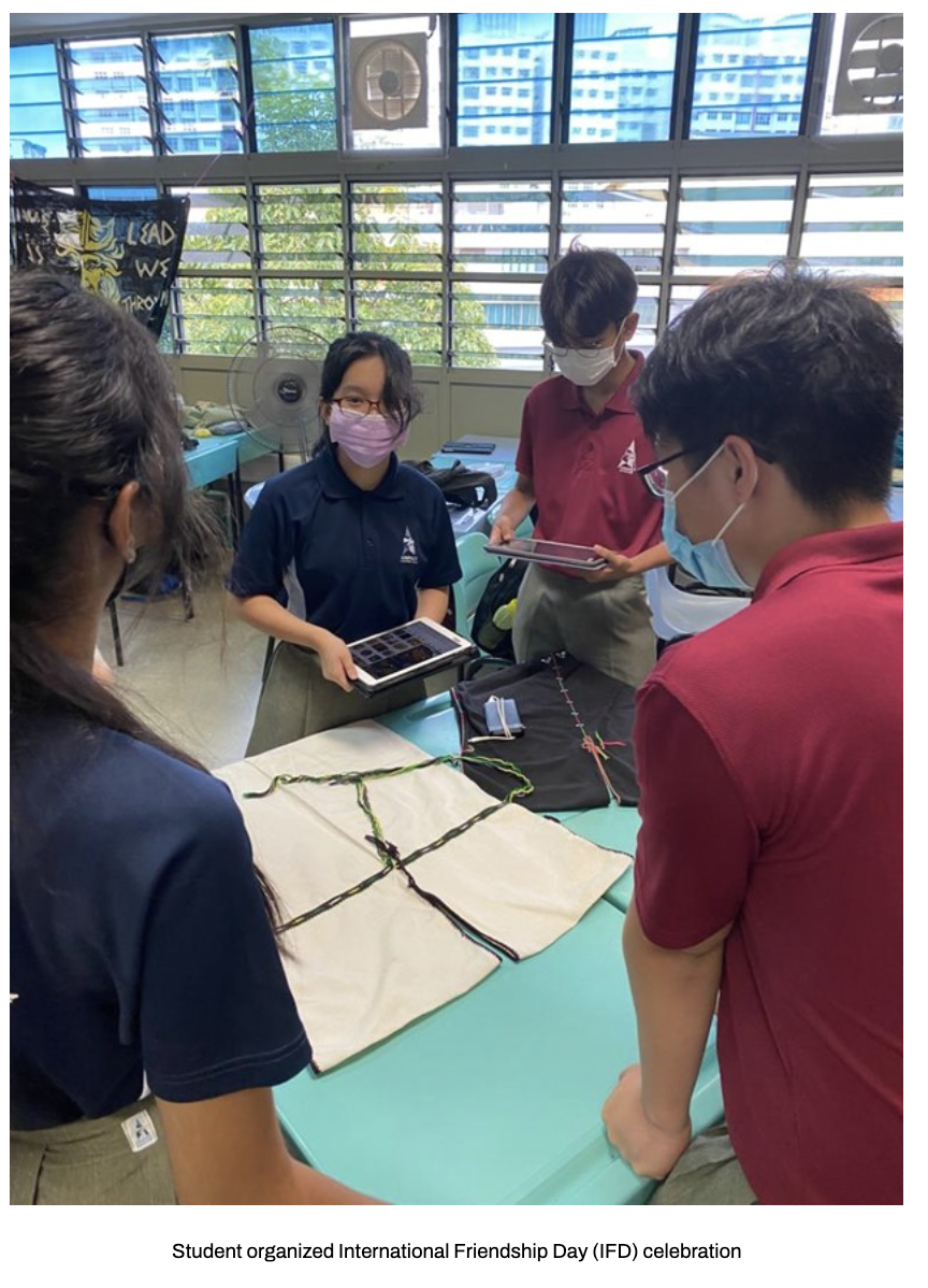 Our students gather around a table with fabric and yarn, two holding tablets.