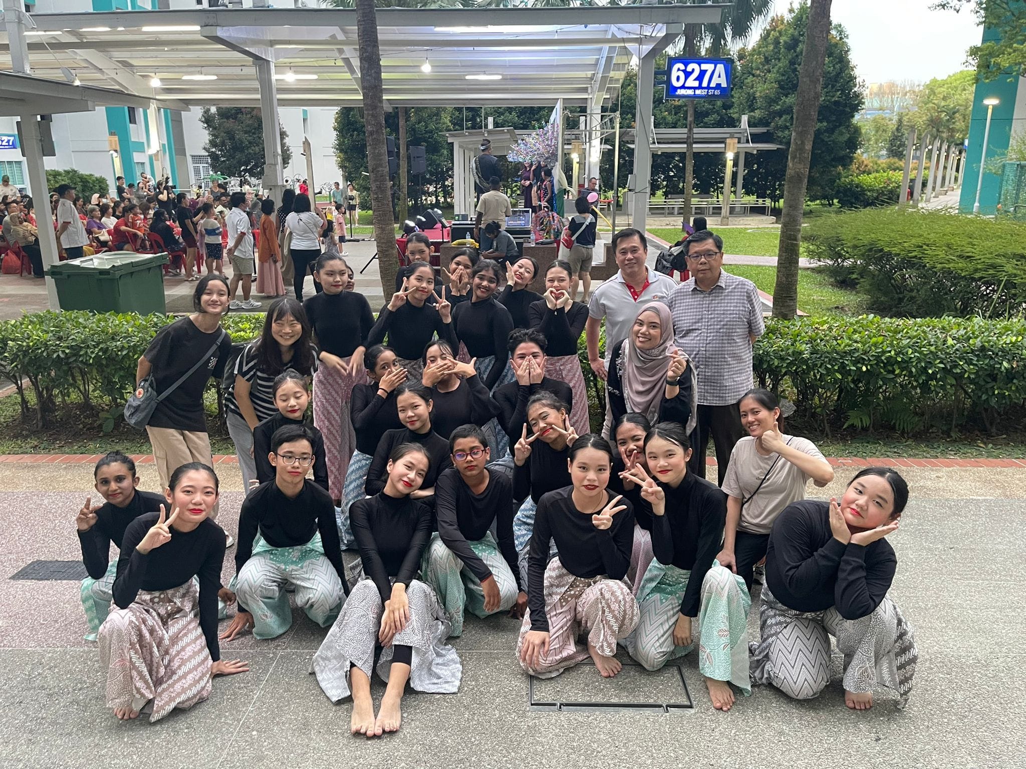 Group of young dancers in black tops and patterned skirts posing outdoors at Jurong West Street 65.