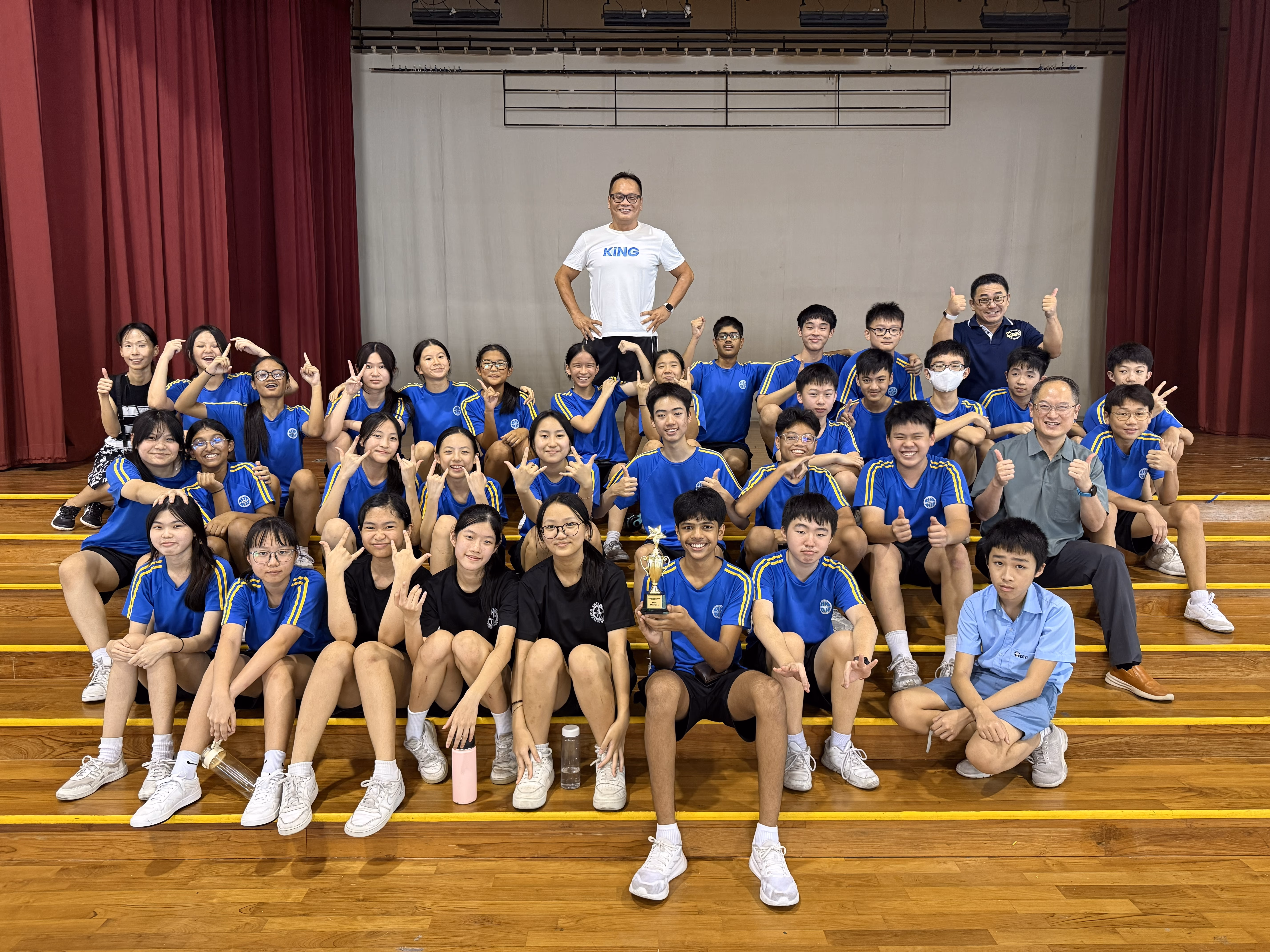 Students and teachers pose with a trophy after a school K-pop competition.