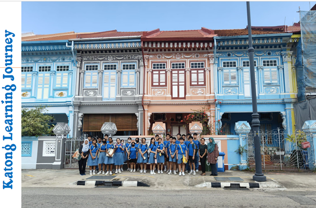 Students in school uniforms pose in front of colorful Peranakan shophouses in Katong, Singapore.