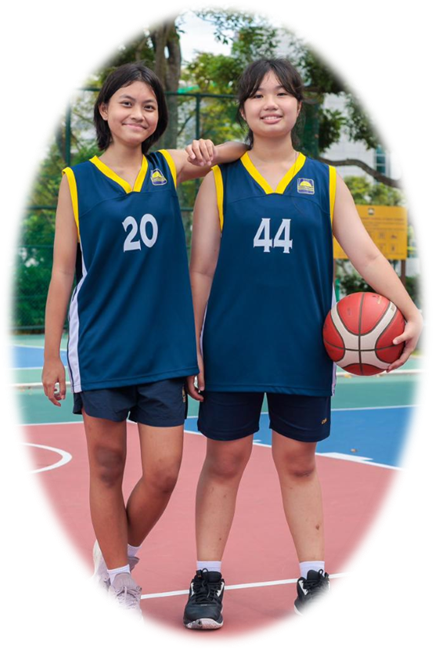 Two girls in navy basketball jerseys numbered 20 and 44 stand on an outdoor court, one holding a basketball.