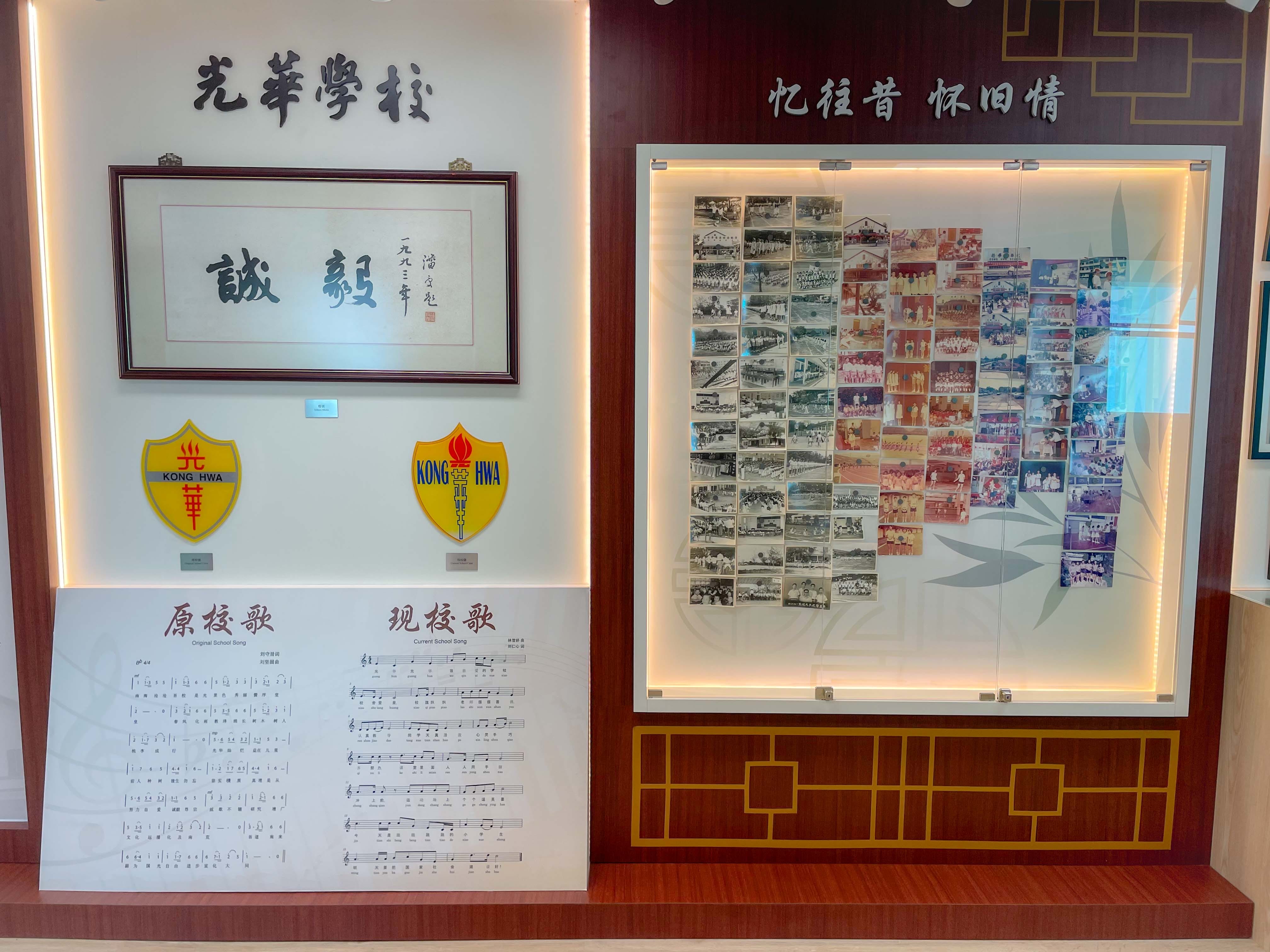 A school display wall with Chinese text, two Kong Hwa shields, sheet music, and a collage of historical photos.