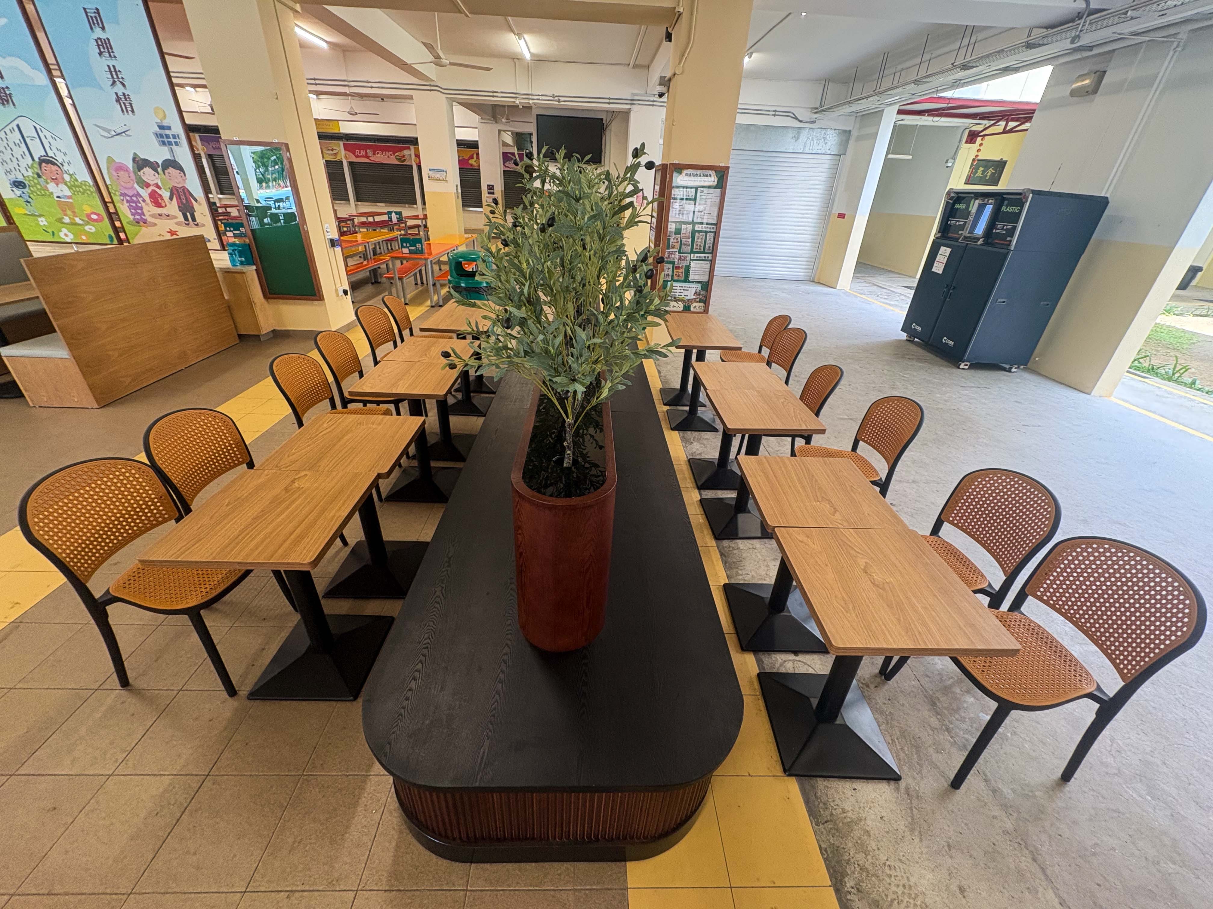 Empty school cafeteria with red and orange tables, benches, and colorful Chinese character murals on the wall.