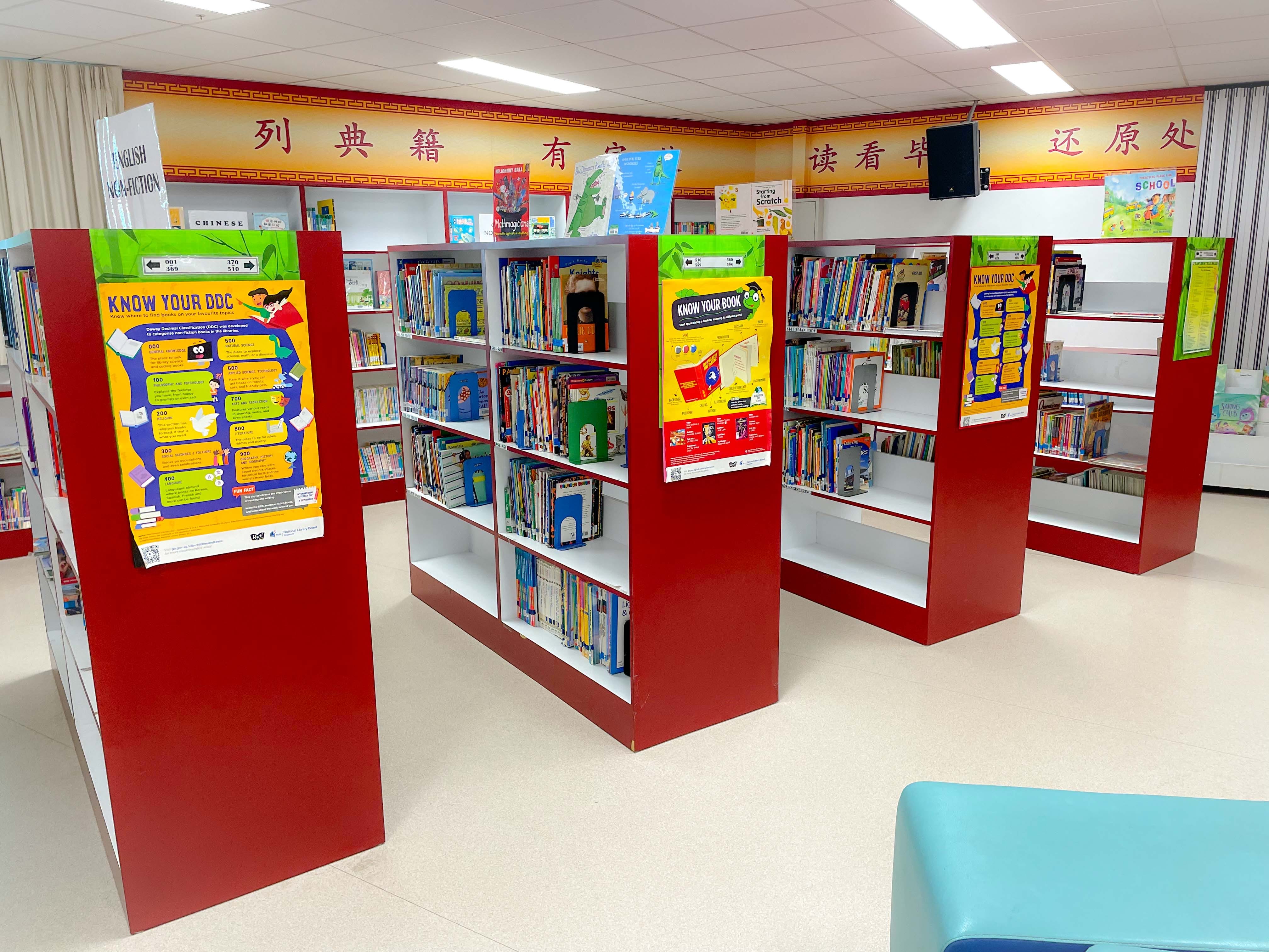 Red and white library shelves filled with colorful books, with Chinese characters on a decorative wall border above.