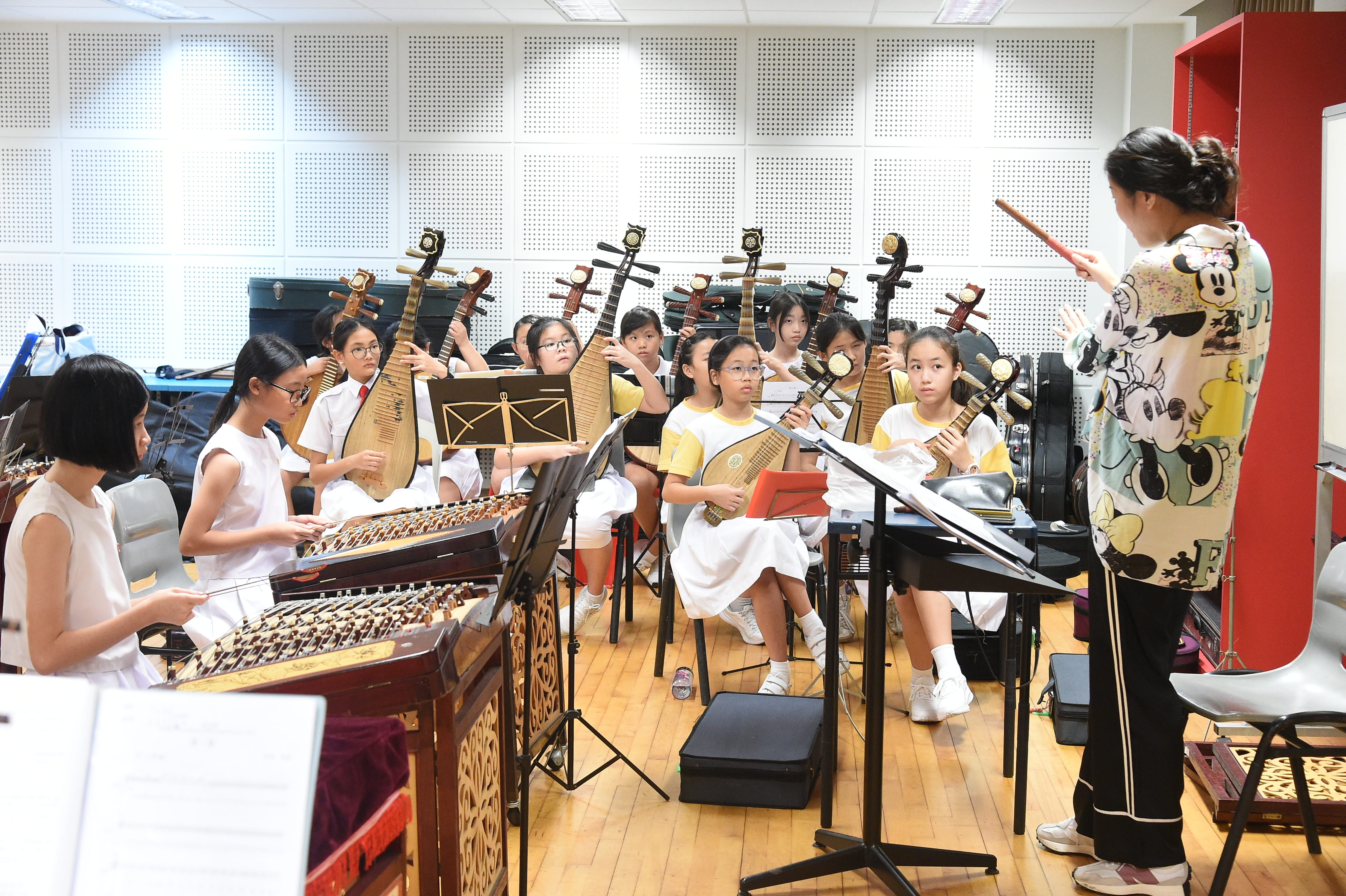 Chinese orchestra students practicing with a conductor