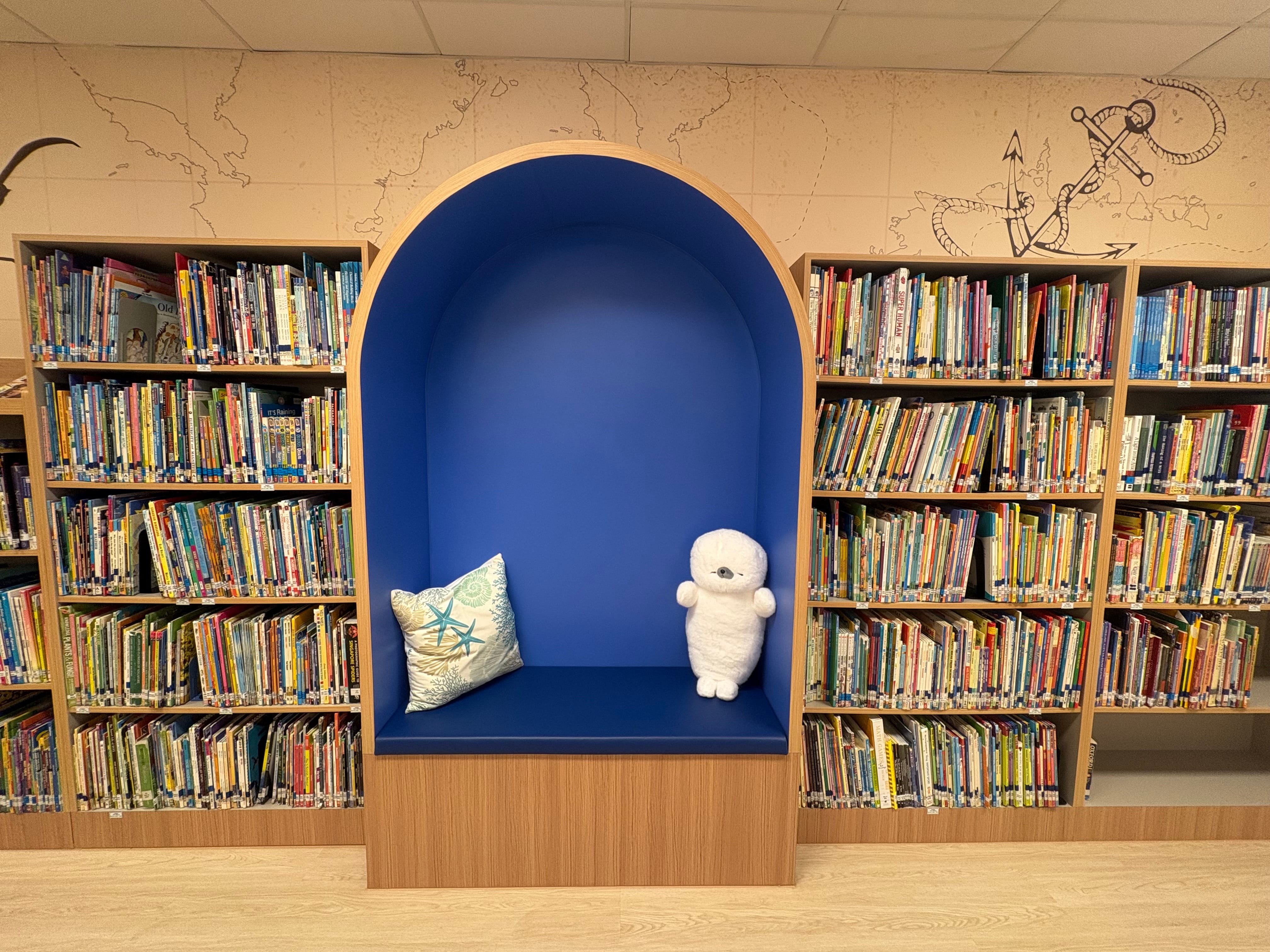 bright school library with a sea exploration theme , showing a cushion corner for reading