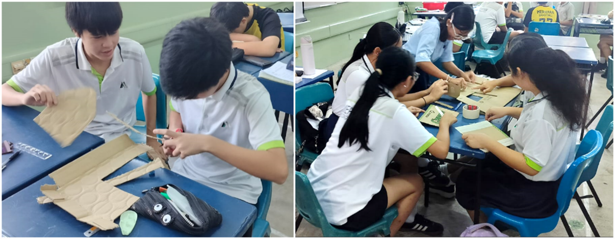 Students in school uniforms work at blue desks, cutting cardboard and crafting projects in a classroom.