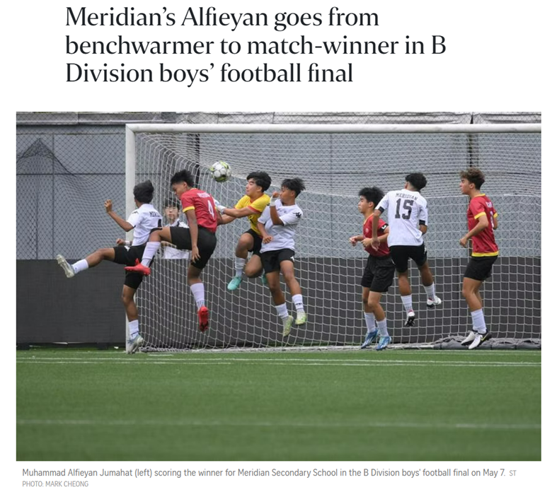 Boys in red and white uniforms jump and contest a header near a football goal during a youth match.