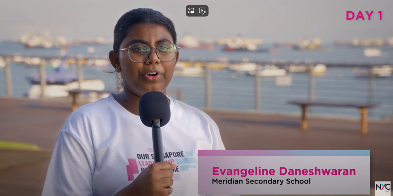 A girl named Evangeline Daneshwaran from Meridian Secondary School speaks into a microphone outdoors near a waterfront.