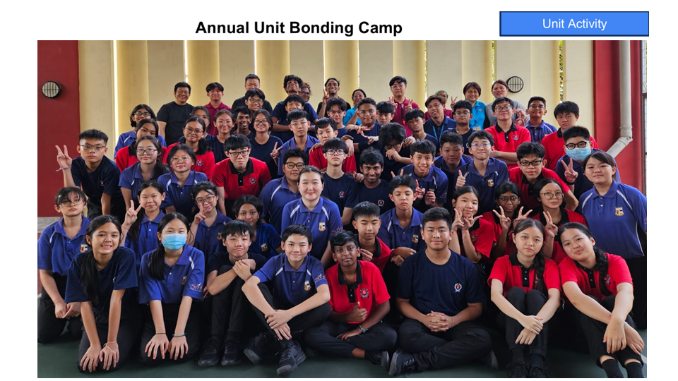 Large group of students in red and blue uniforms posing together indoors for Annual Unit Bonding Camp.