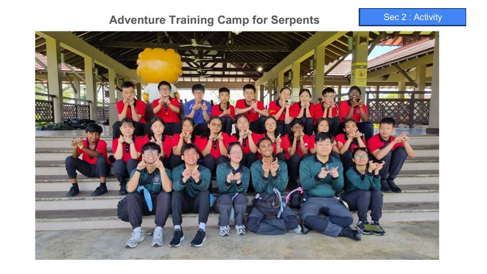 Group of students in red and dark uniforms posing on outdoor steps under a pavilion at an adventure camp.