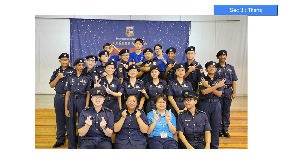 Group of students and teachers in navy uniforms posing in front of a Serangoon Secondary School banner.