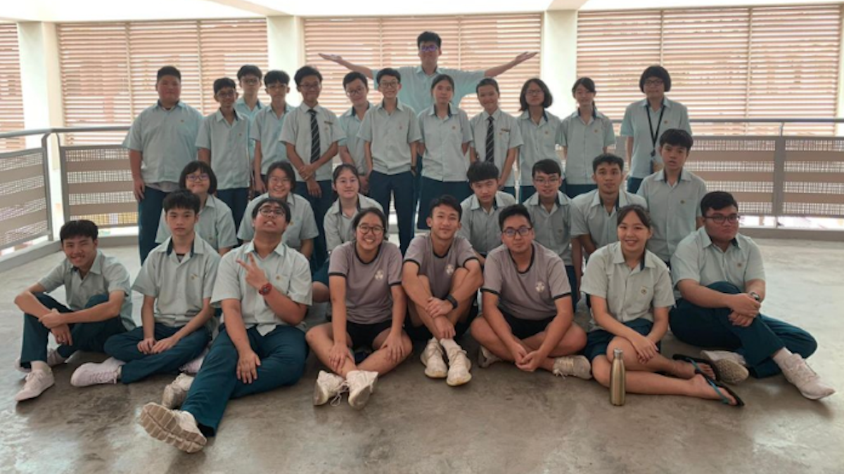 A group of people wearing what looks like uniforms in shades of green posing in front of a camera.