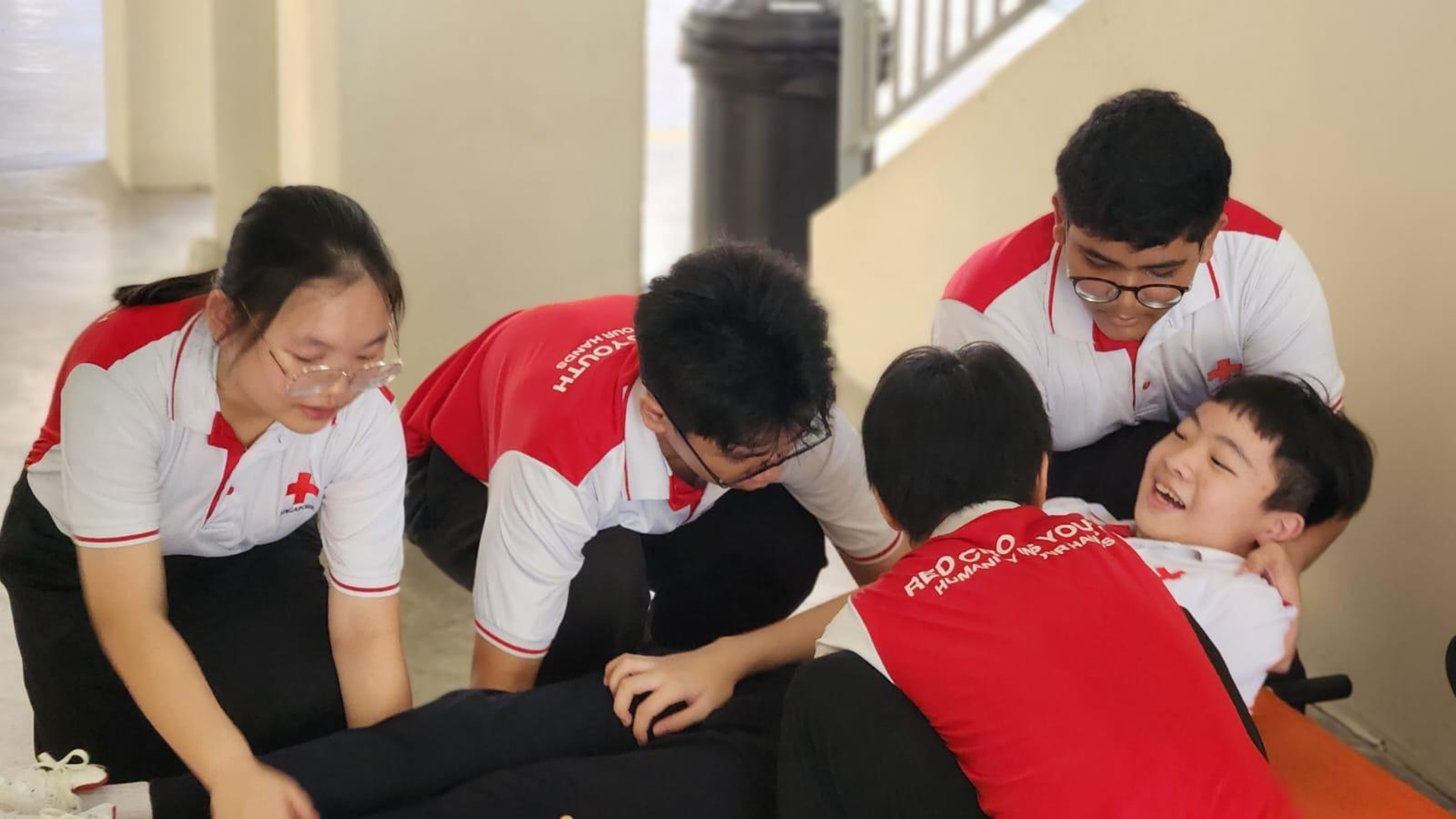 Four Red Cross Youth cadets practicing casualty positioning on a stretcher.