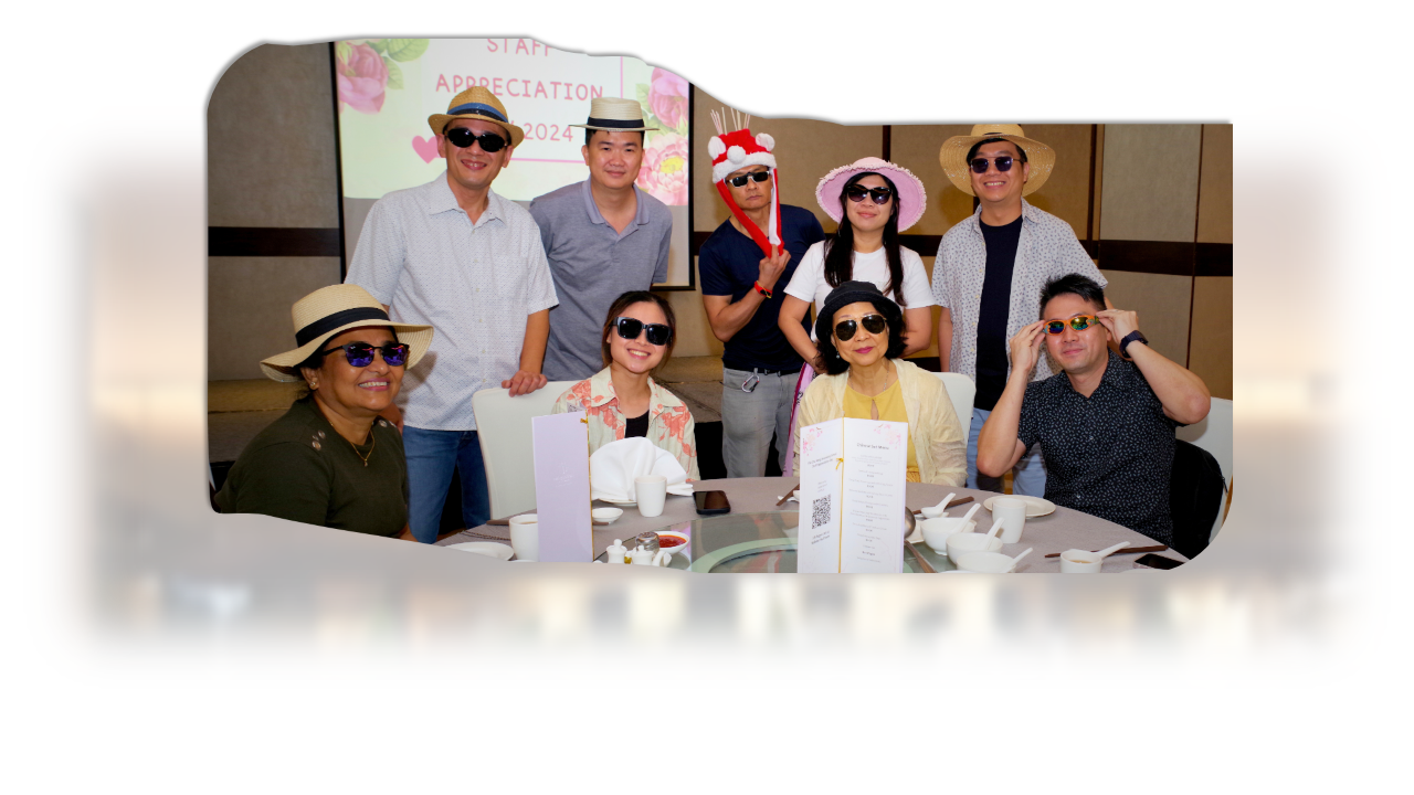 Nine people wearing hats and sunglasses pose at a 2024 Staff Appreciation event around a dining table.