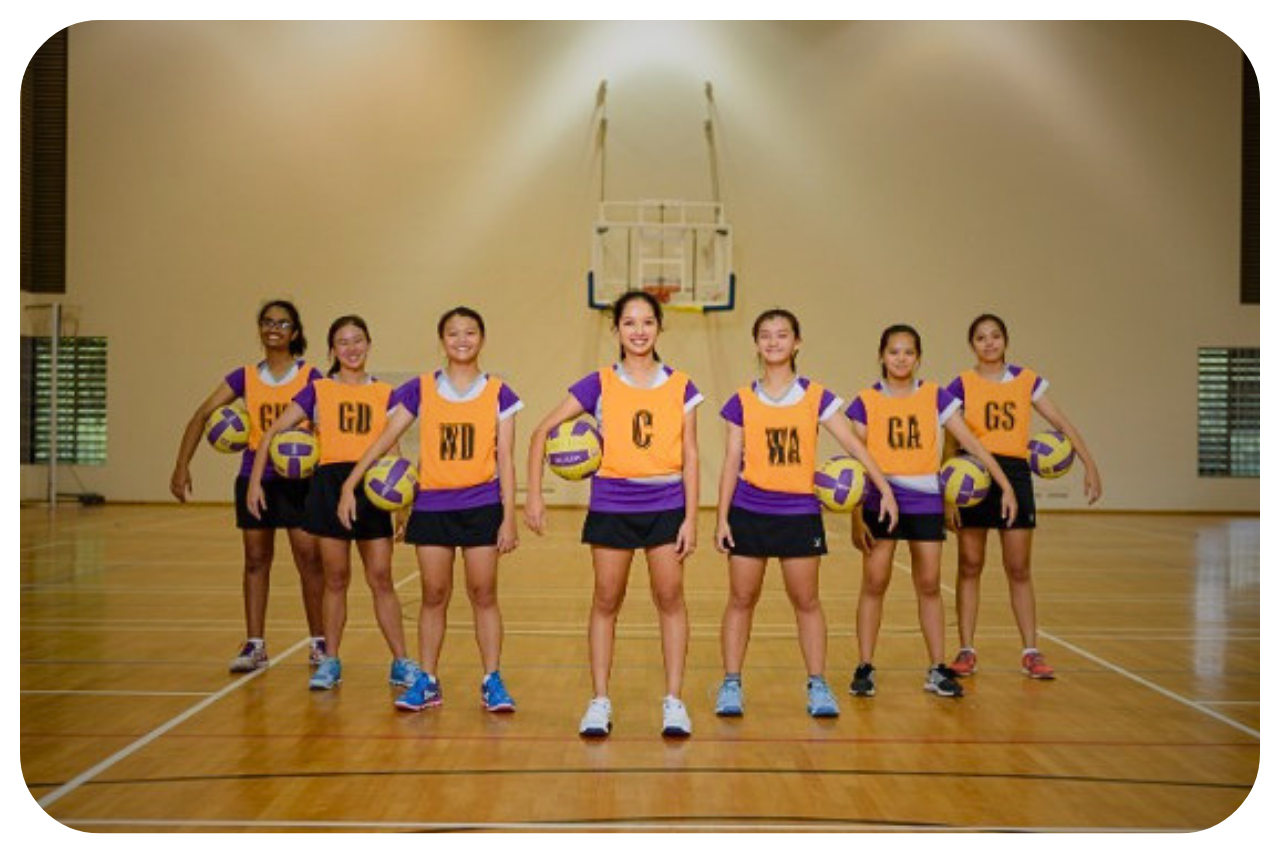 A group of girls in formation with balls under their arms.