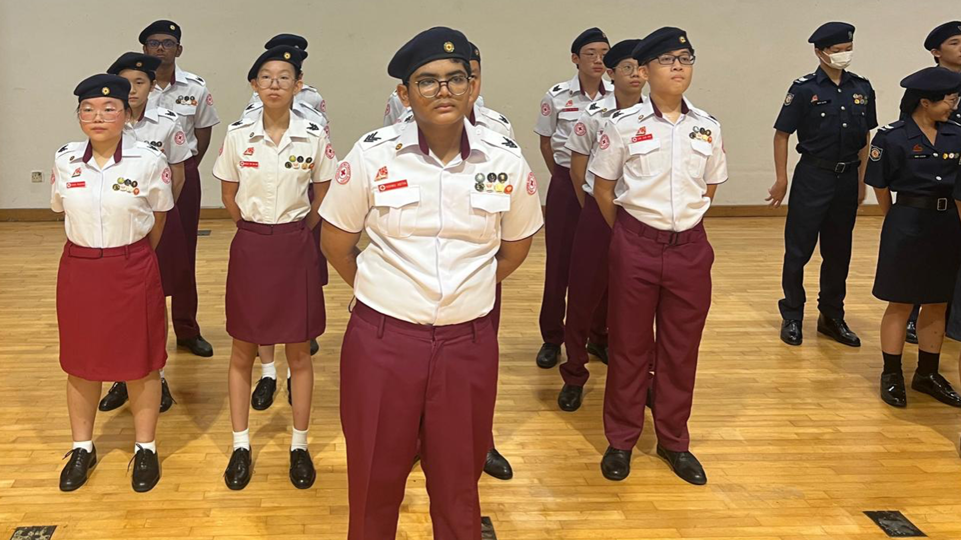 Front view of Red Cross Youth cadets in full uniform standing in formation inside a hall.