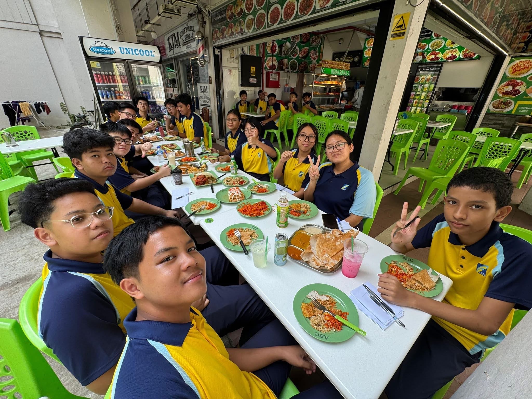students seated at a long table with Indian Muslim food