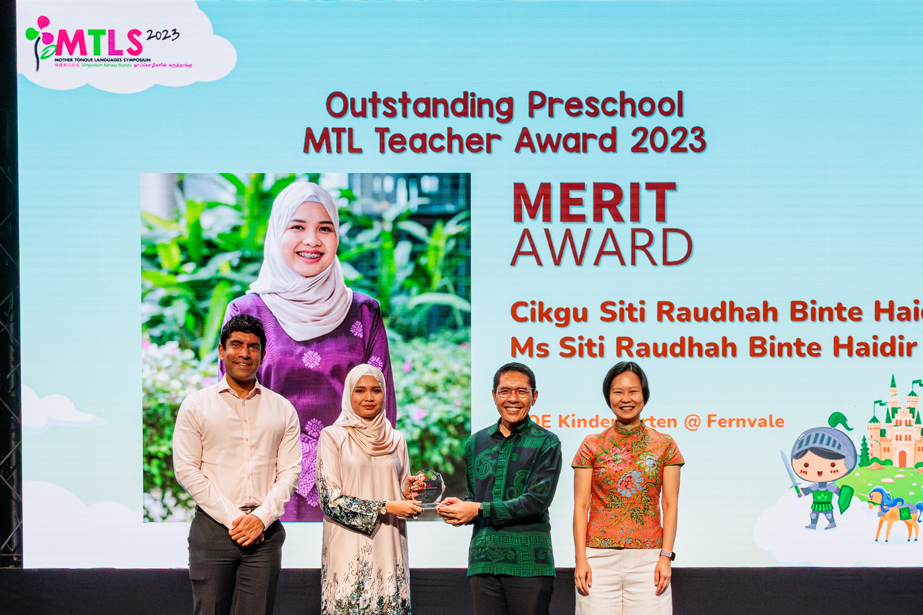 Four people stand on stage at MTLS 2023 as a Merit Award is presented for Outstanding Preschool MTL Teacher.