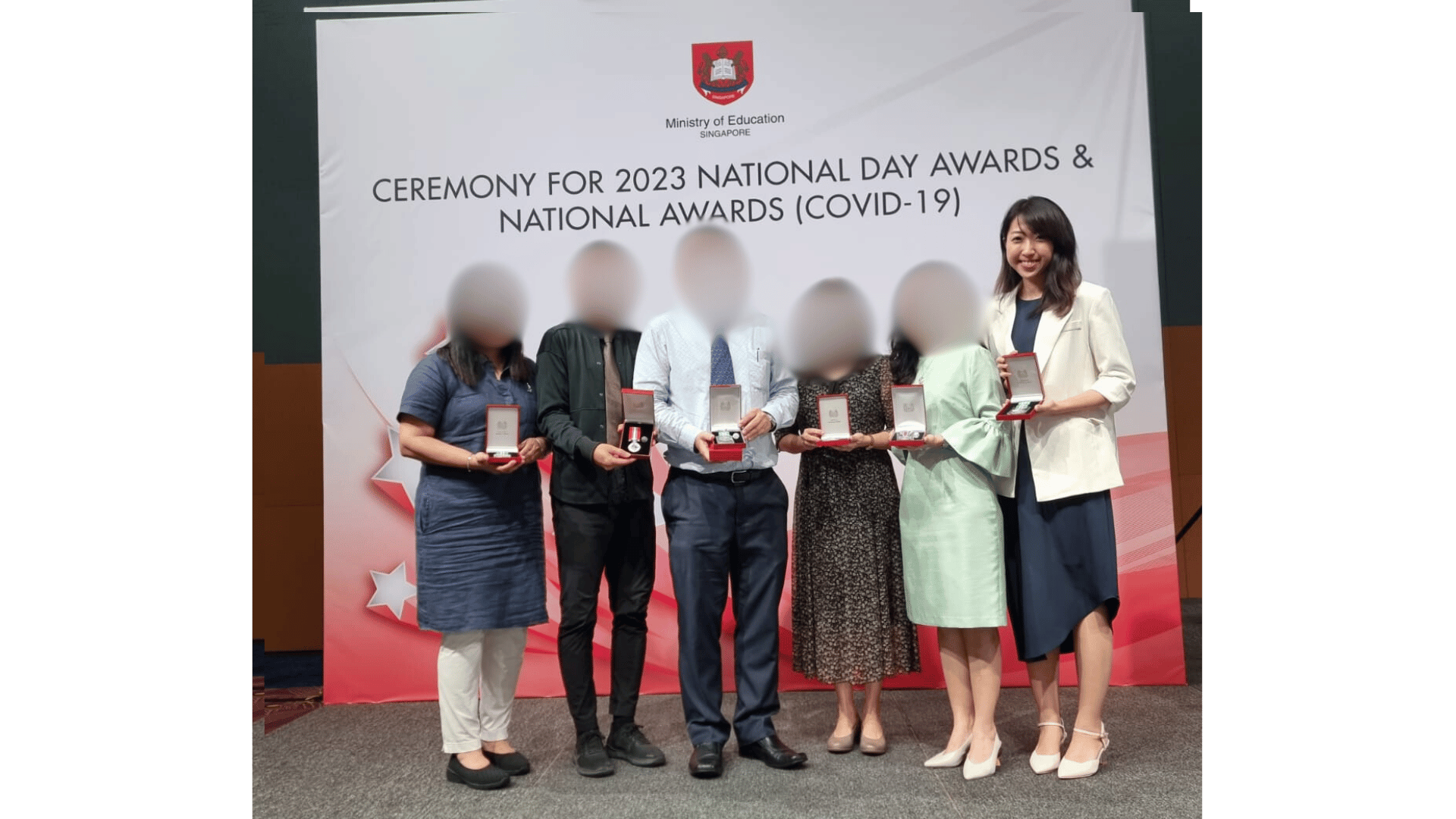Five people holding award boxes stand before a banner reading Ceremony for 2023 National Day Awards and National Awards COVID-19.