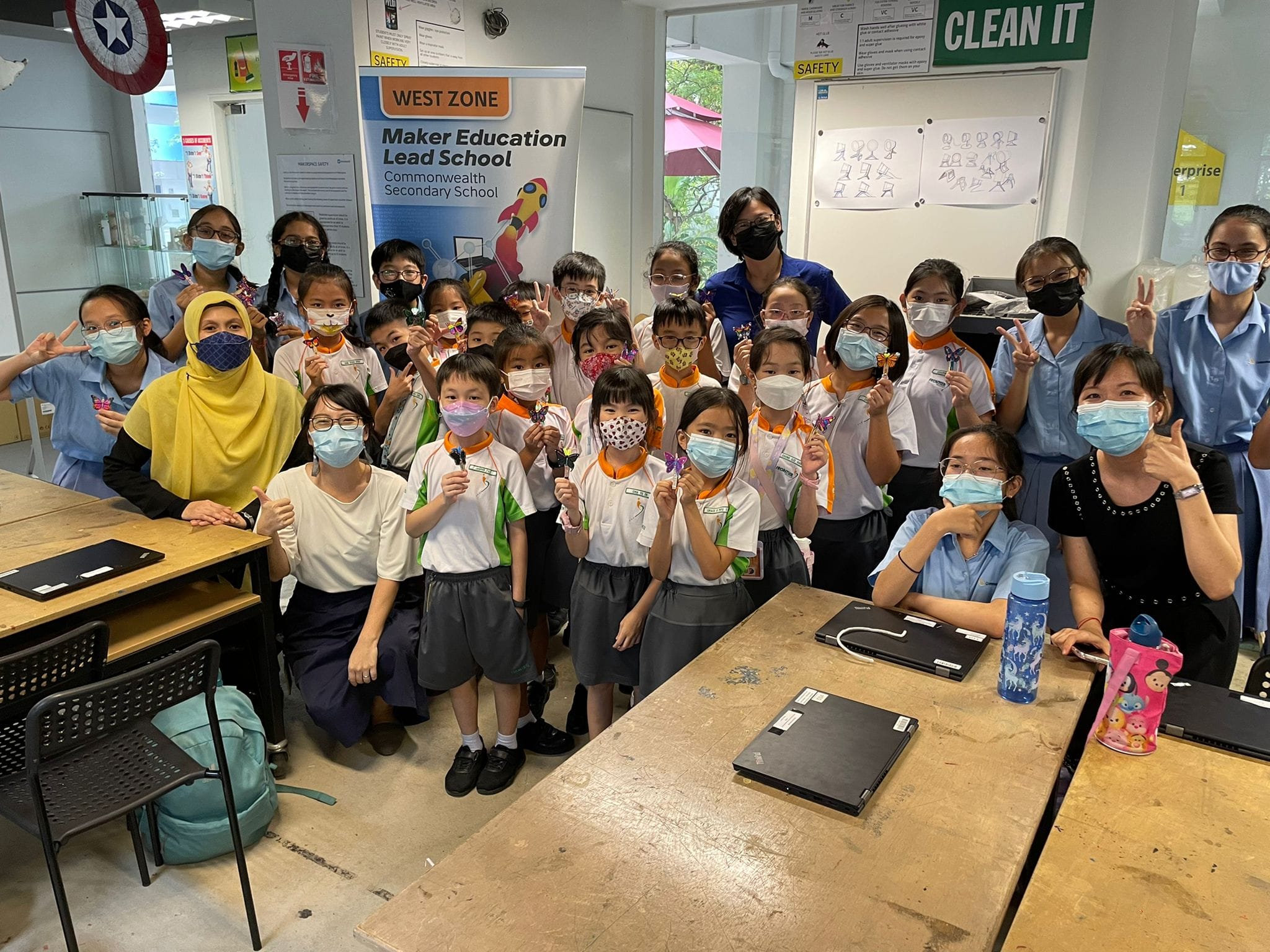 Group of masked students and teachers pose in a classroom at West Zone Maker Education Lead School.