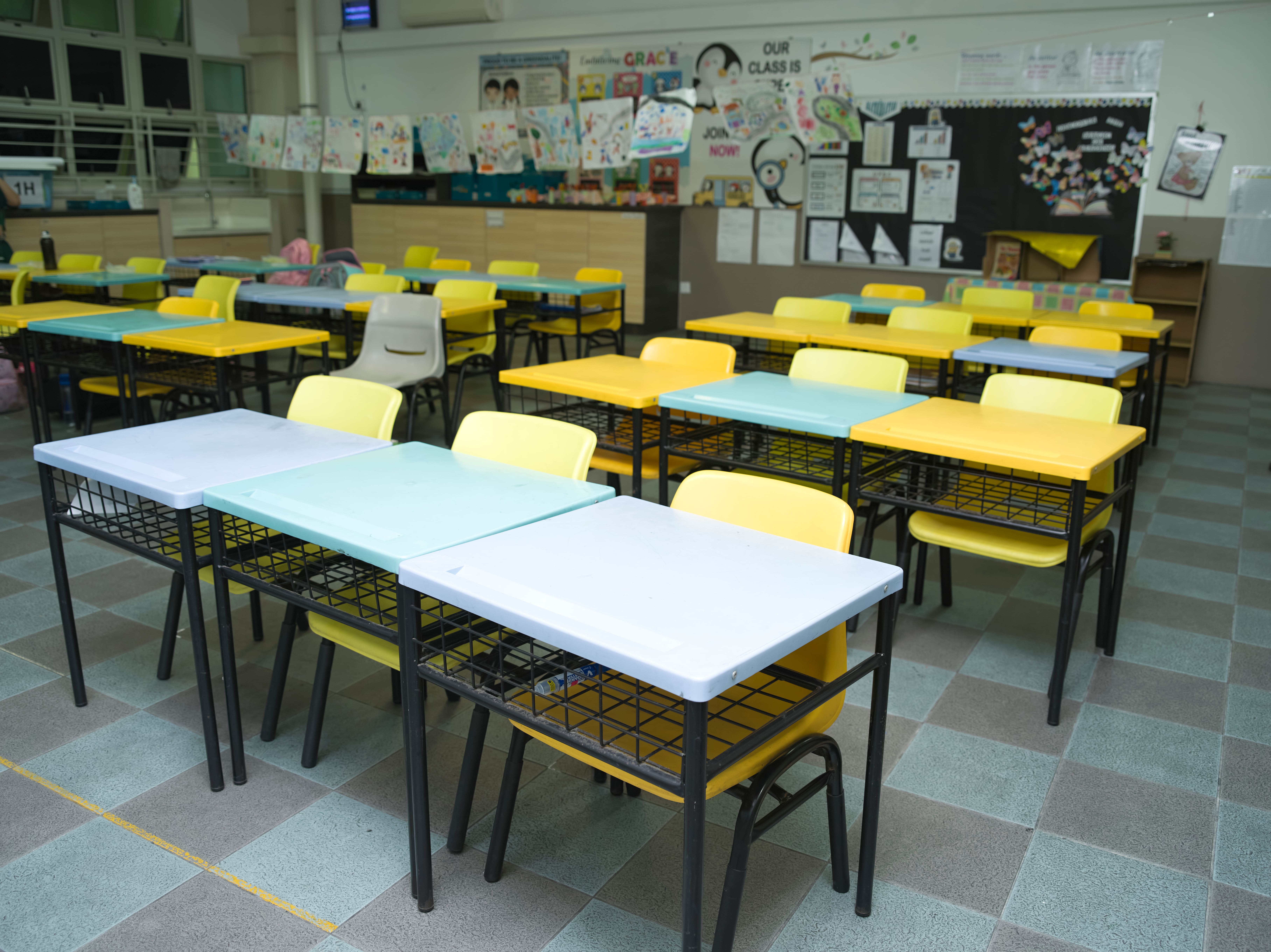 Bright classroom with colourful desks, chairs and student learning displays.