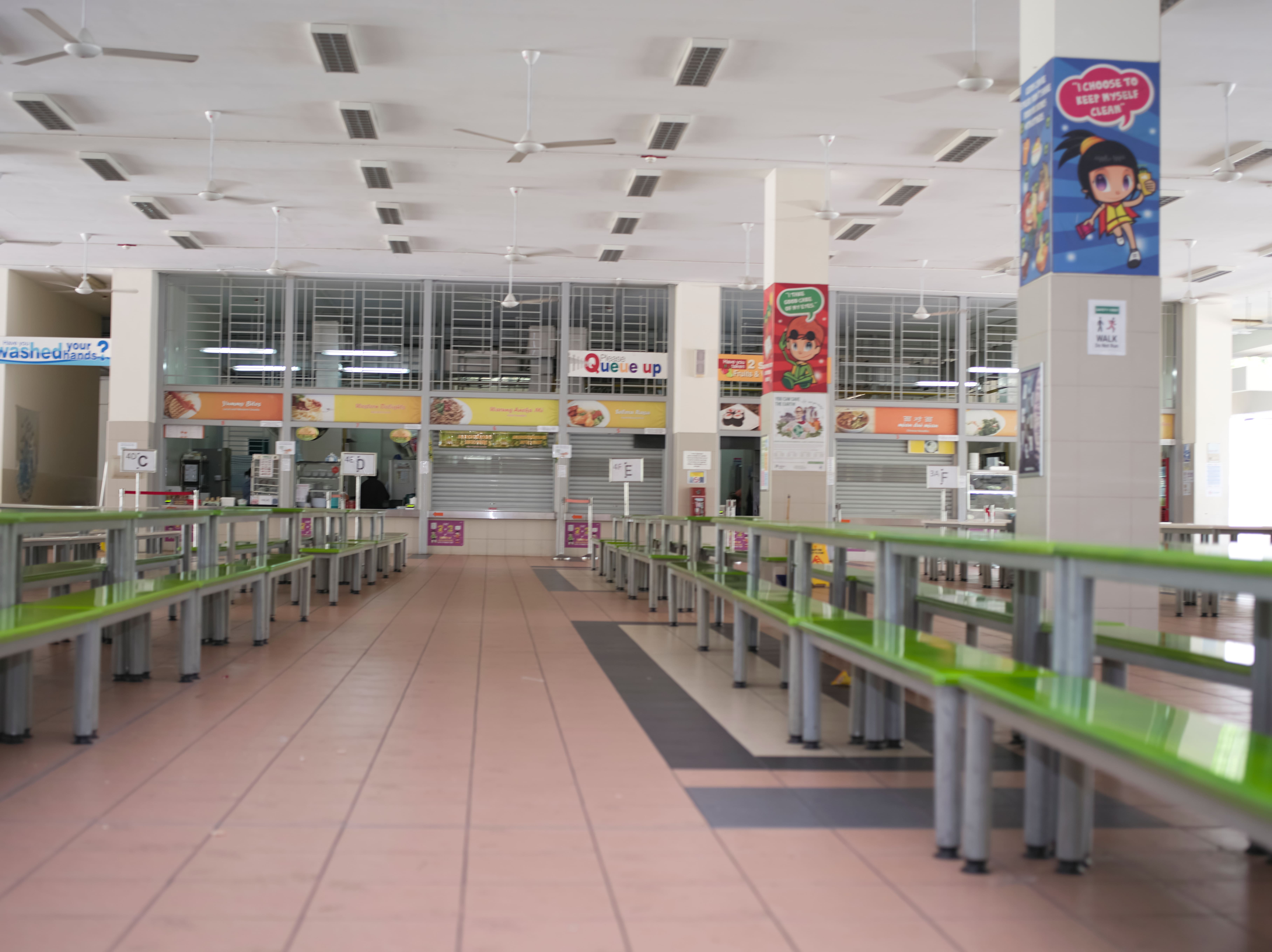School canteen with food stalls, dining tables and colourful displays.
