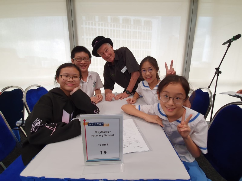 Four students and an adult pose at a table labeled Mayflower Primary School Team 2, number 19.