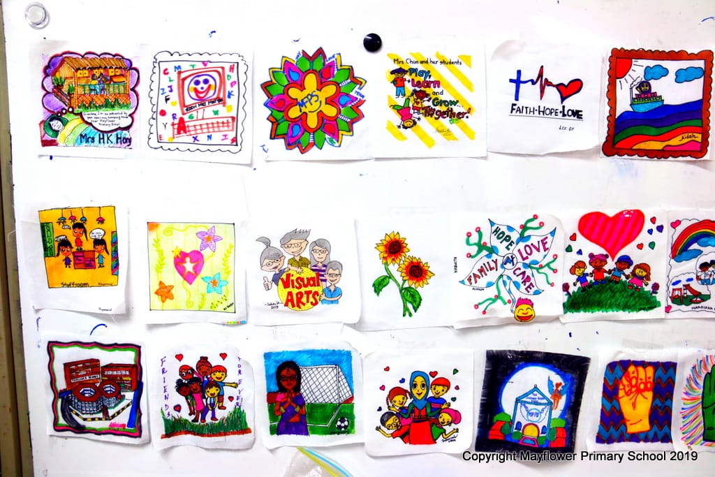 Colorful student artworks pinned to a white wall, featuring themes of family, faith, hope, love, and Visual Arts.