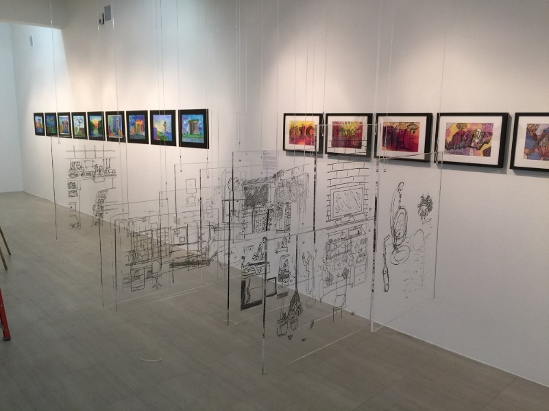 Gallery room with colorful framed artworks on white walls and transparent panels with black line drawings in the foreground.