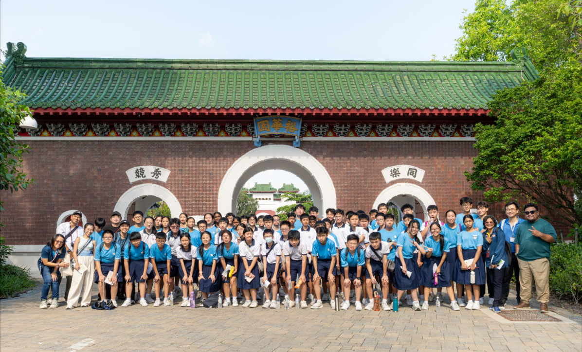 Infocomm club students posing in front of a traditional Chinese brick gate with green tiled roof.