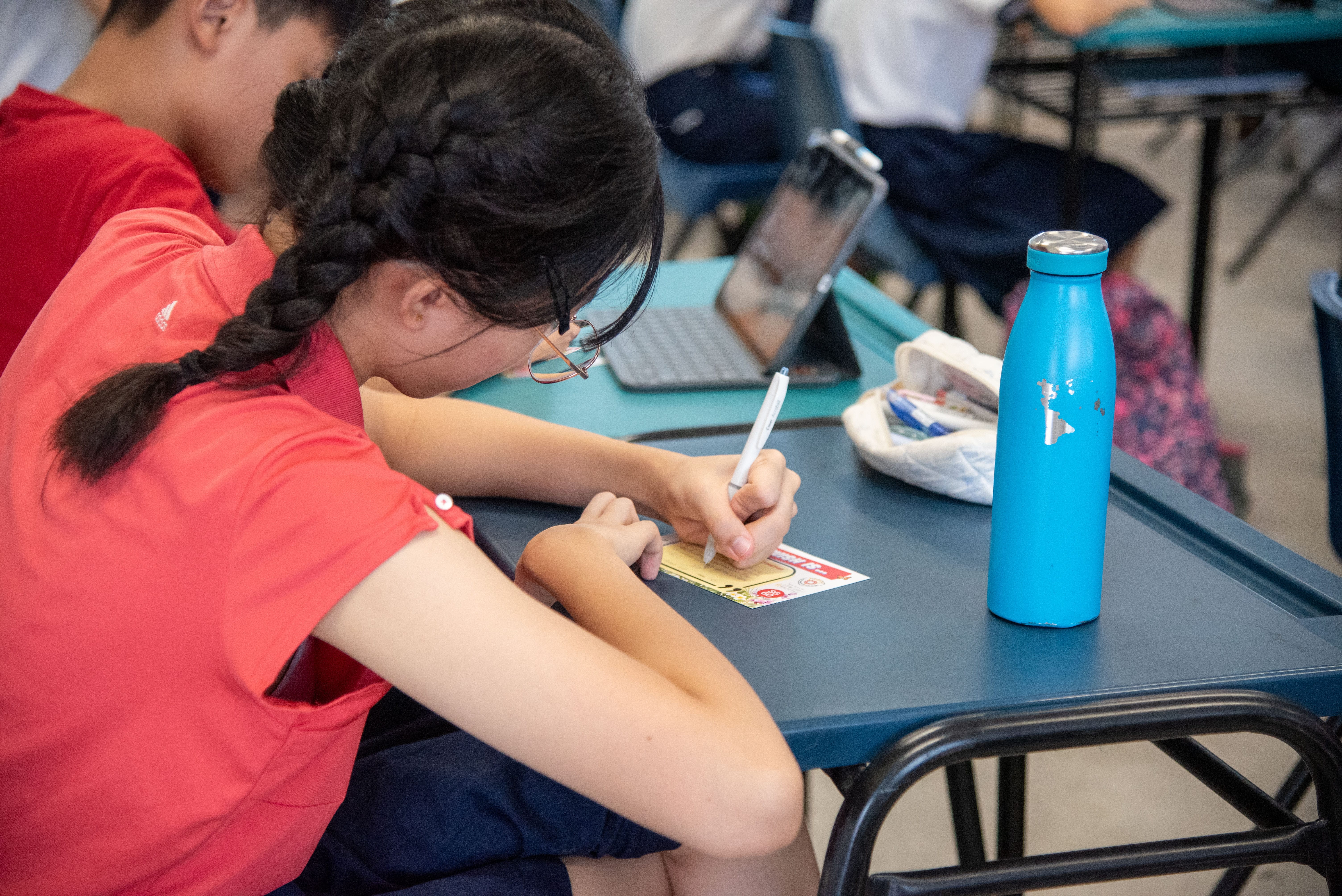 A student hunched over her table as she writes her heartfelt wishes for Singapore.