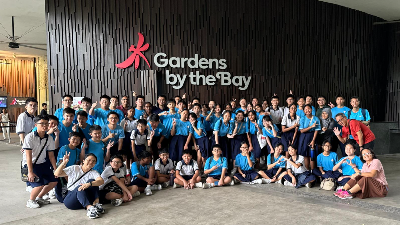 Infocomm students posing in front of the Gardens by the Bay sign in Singapore.