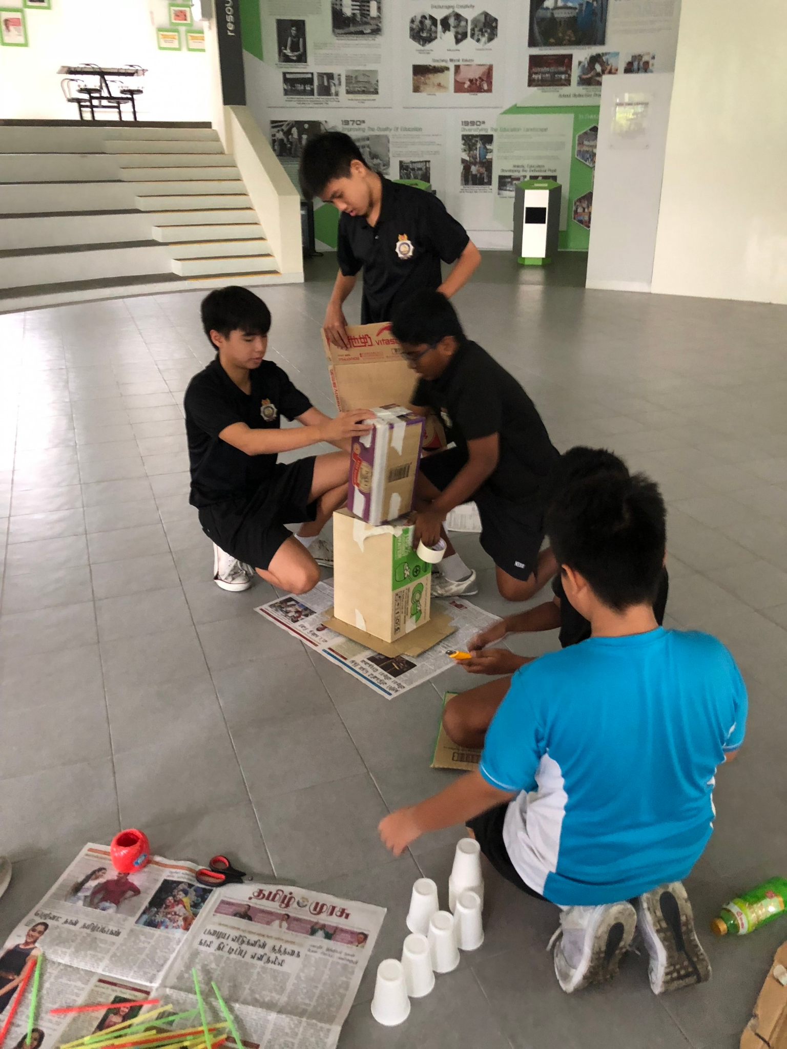 Students coming together to build a structure out of recyclable materials.