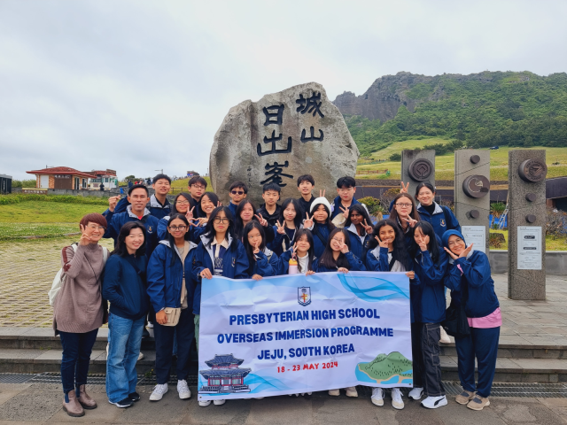 Group of students holding a banner for Presbyterian High School Overseas Immersion Programme in Jeju, South Korea.