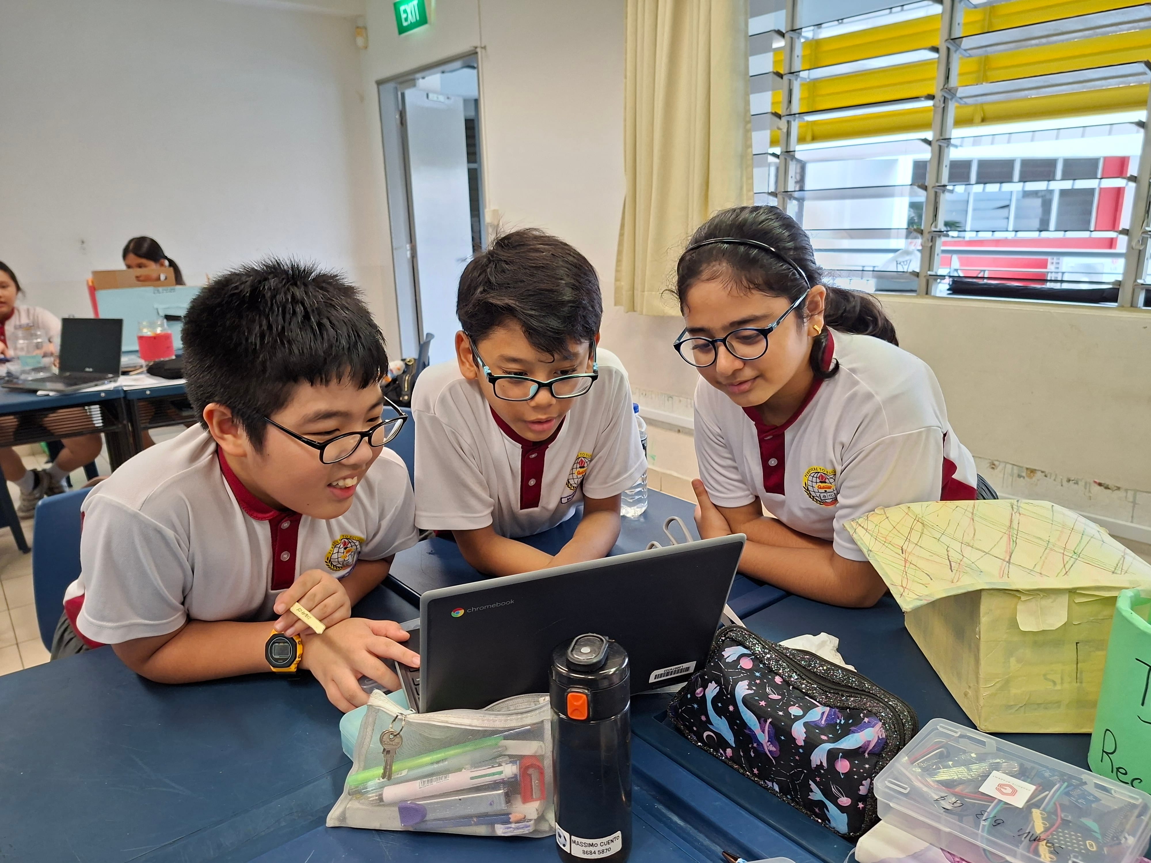 Three students discussing on project with a chromebook