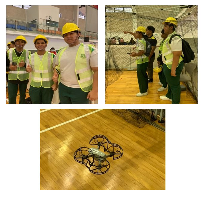 Three photos show students in yellow hard hats and safety vests at an indoor drone event, with a small drone on a gym floor.