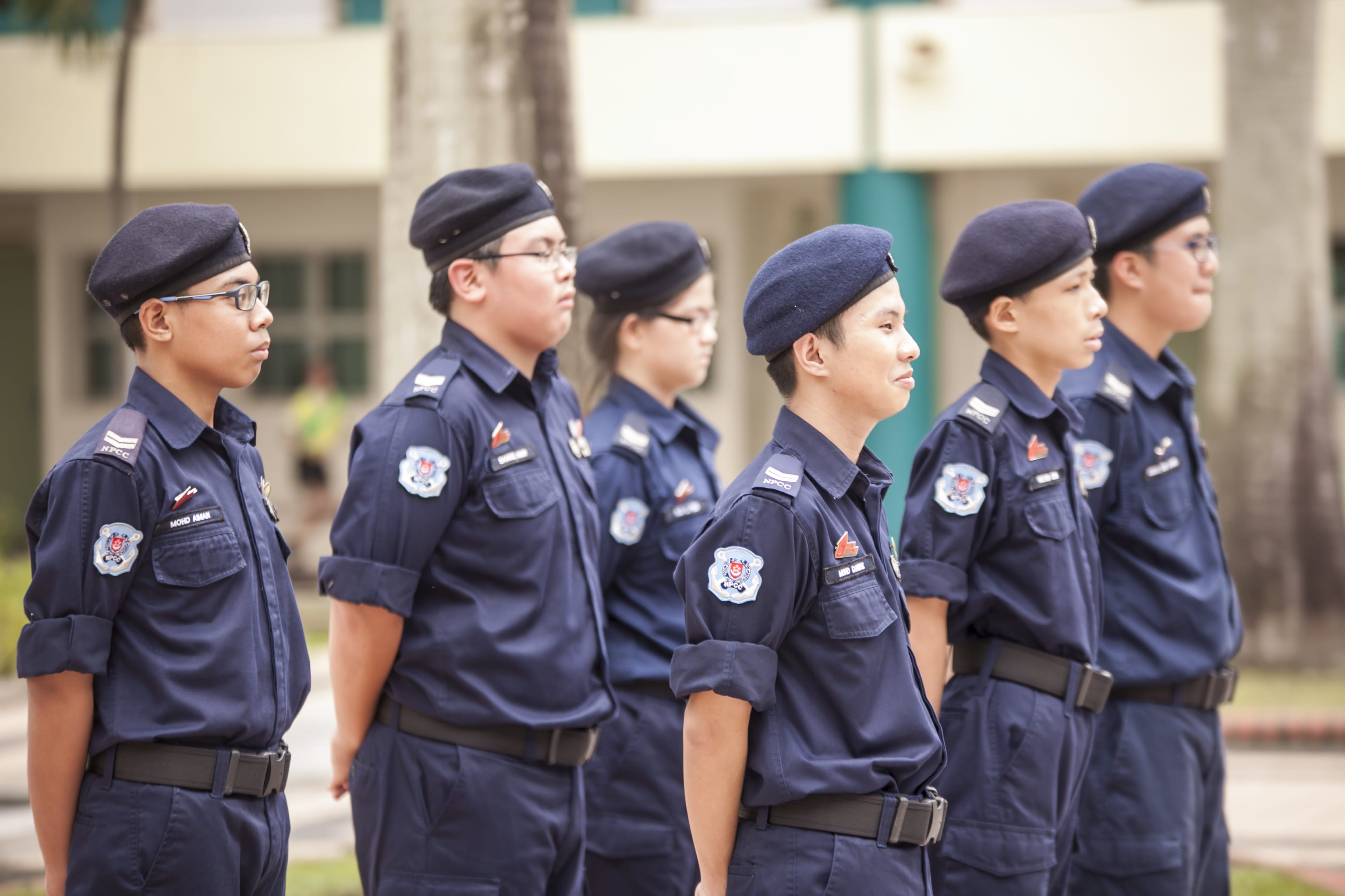 Six young cadets in navy blue NPCC uniforms and berets stand at attention outdoors.