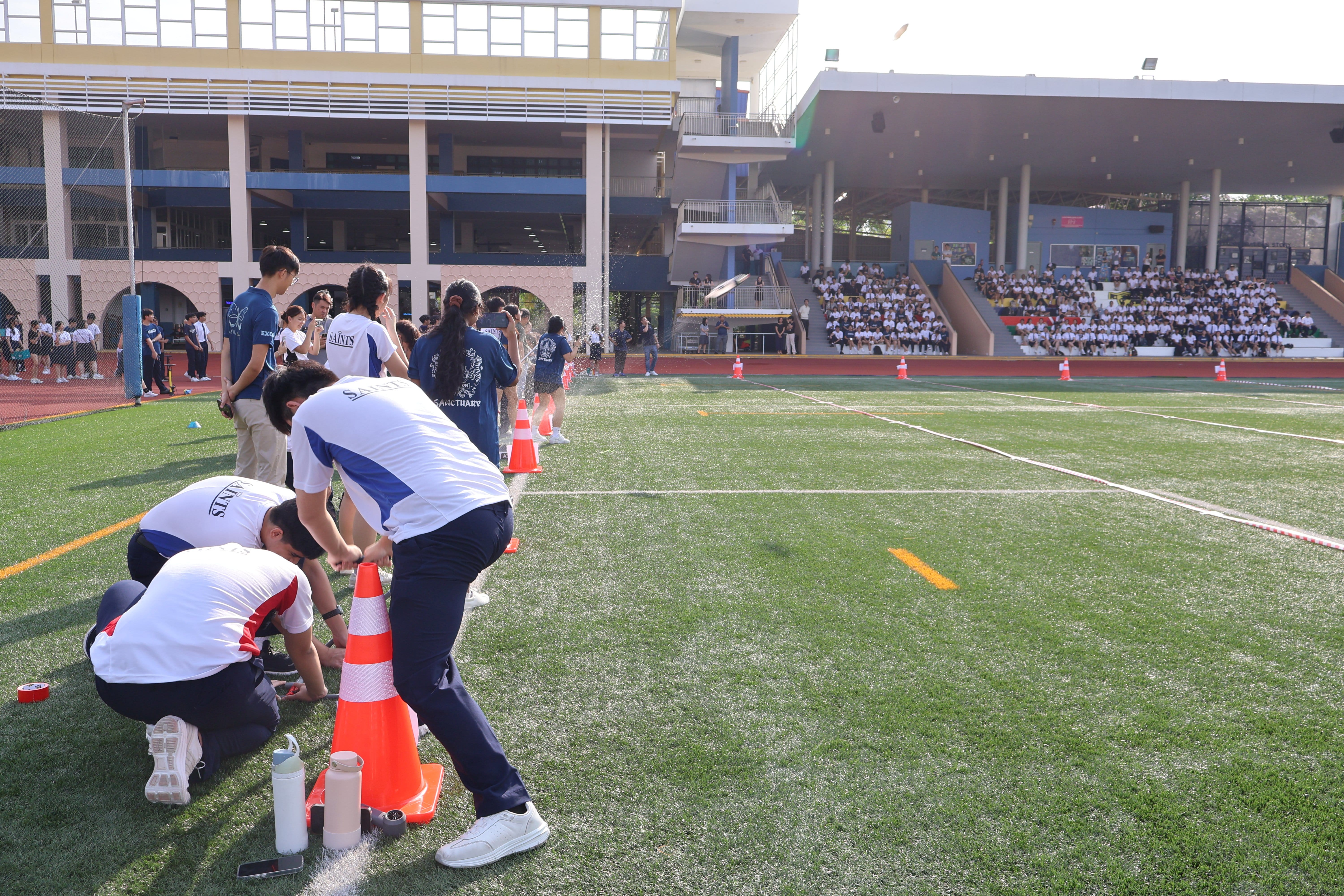 Students getting ready to fire their air-propelled rockets made from recycled material at the school's field.